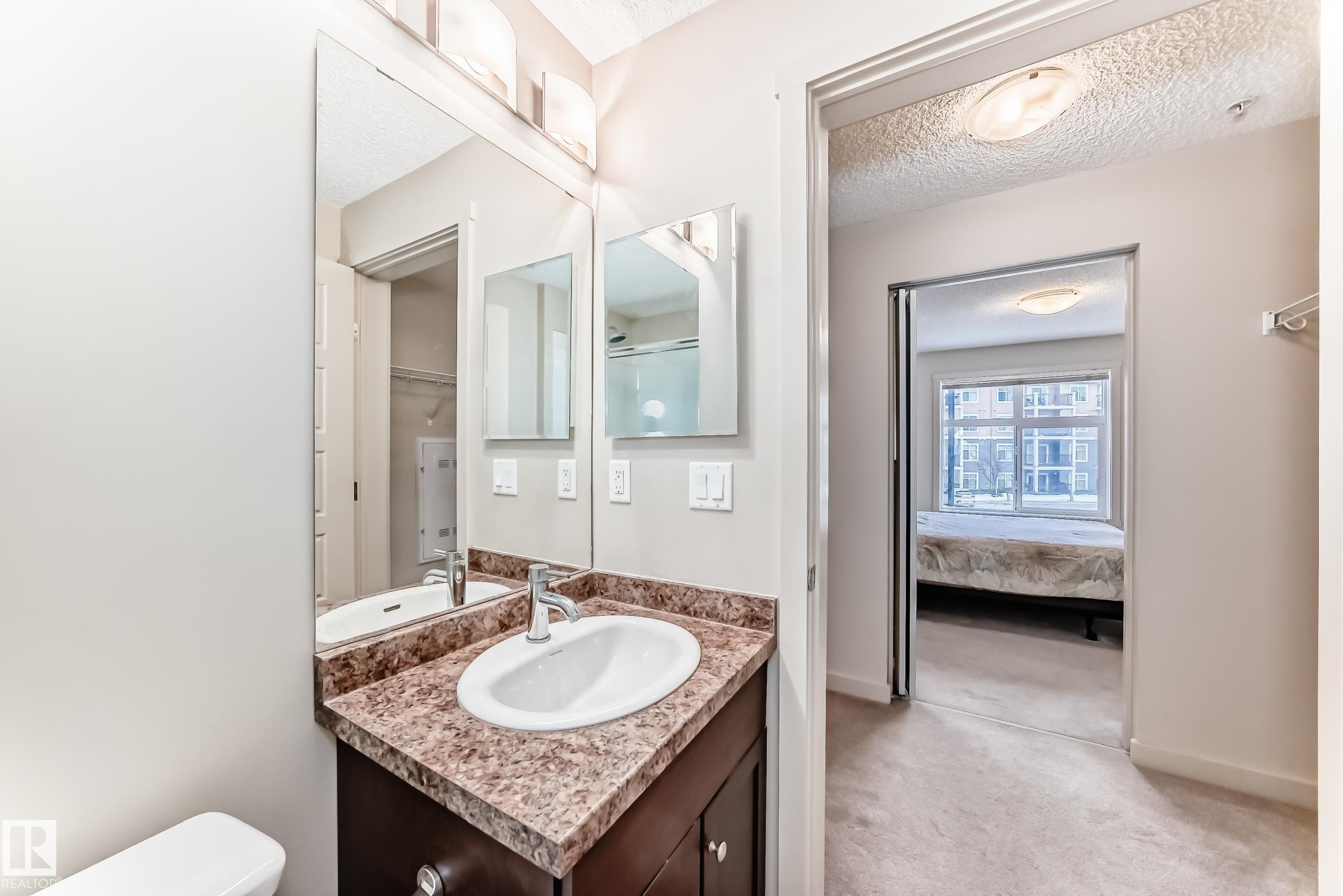Bathroom featuring vanity, light carpet, a textured ceiling, and connected bathroom - 229 6076 Schonsee Way, Edmonton, AB - Indoor Photo Showing Bathroom