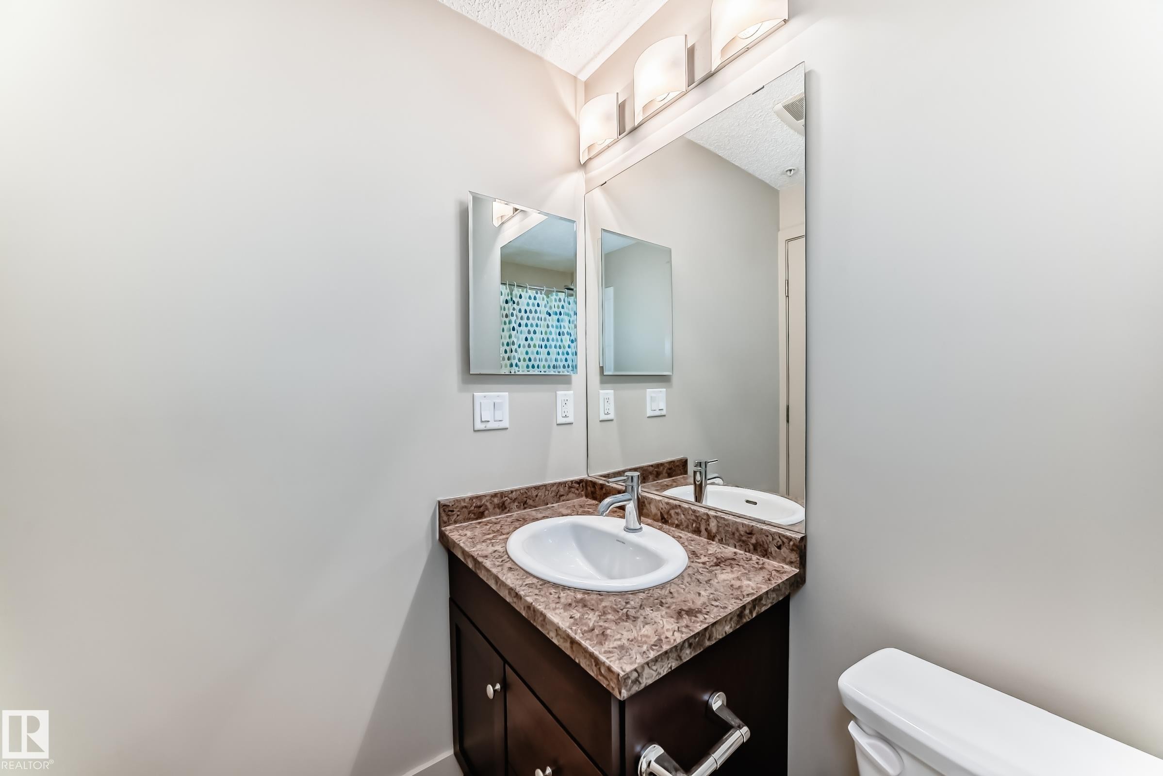Bathroom featuring a textured ceiling, vanity, and a shower with shower curtain - 229 6076 Schonsee Way, Edmonton, AB - Indoor Photo Showing Bathroom