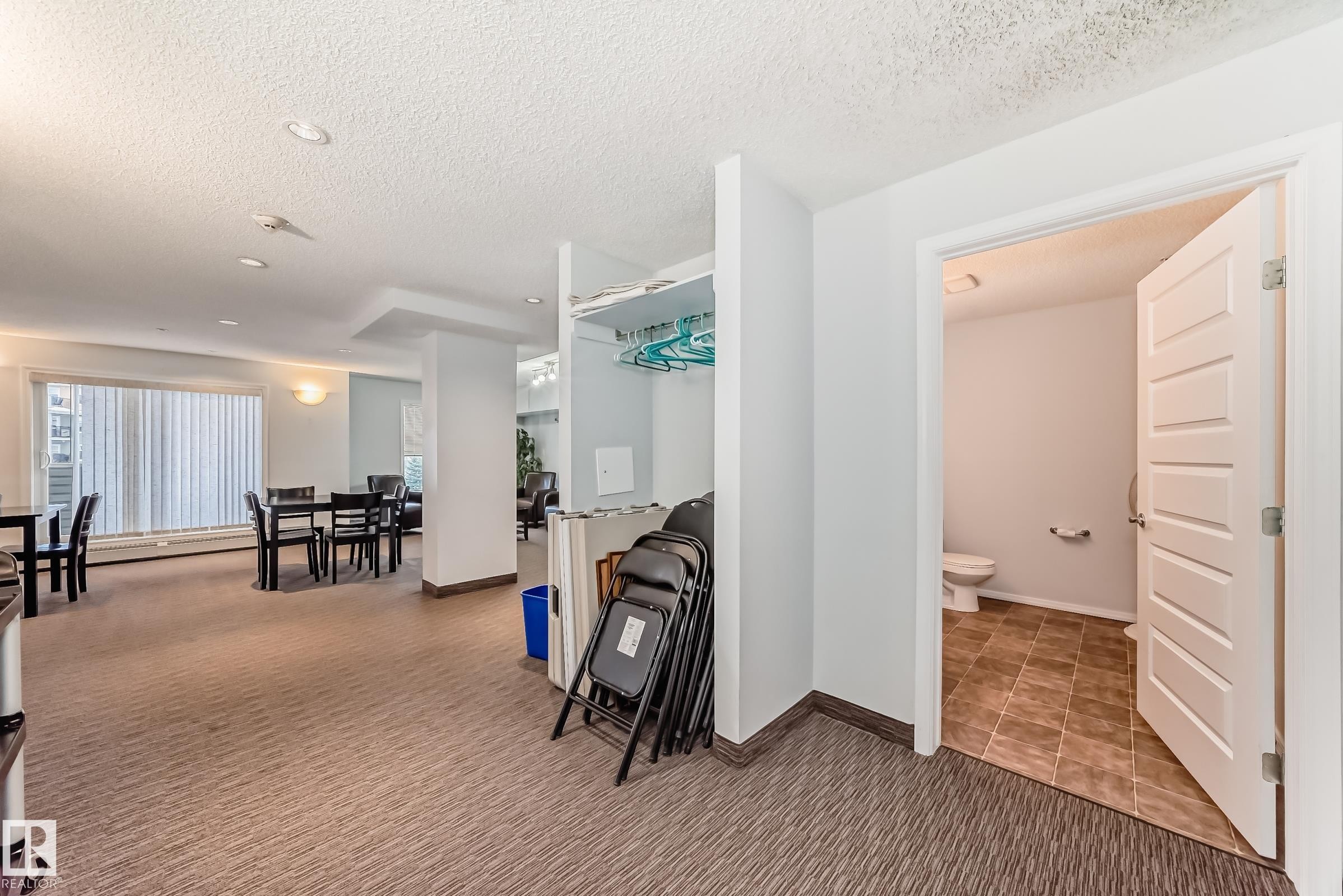Social room area featuring carpet, a textured ceiling, and baseboard heating - 229 6076 Schonsee Way, Edmonton, AB - Indoor
