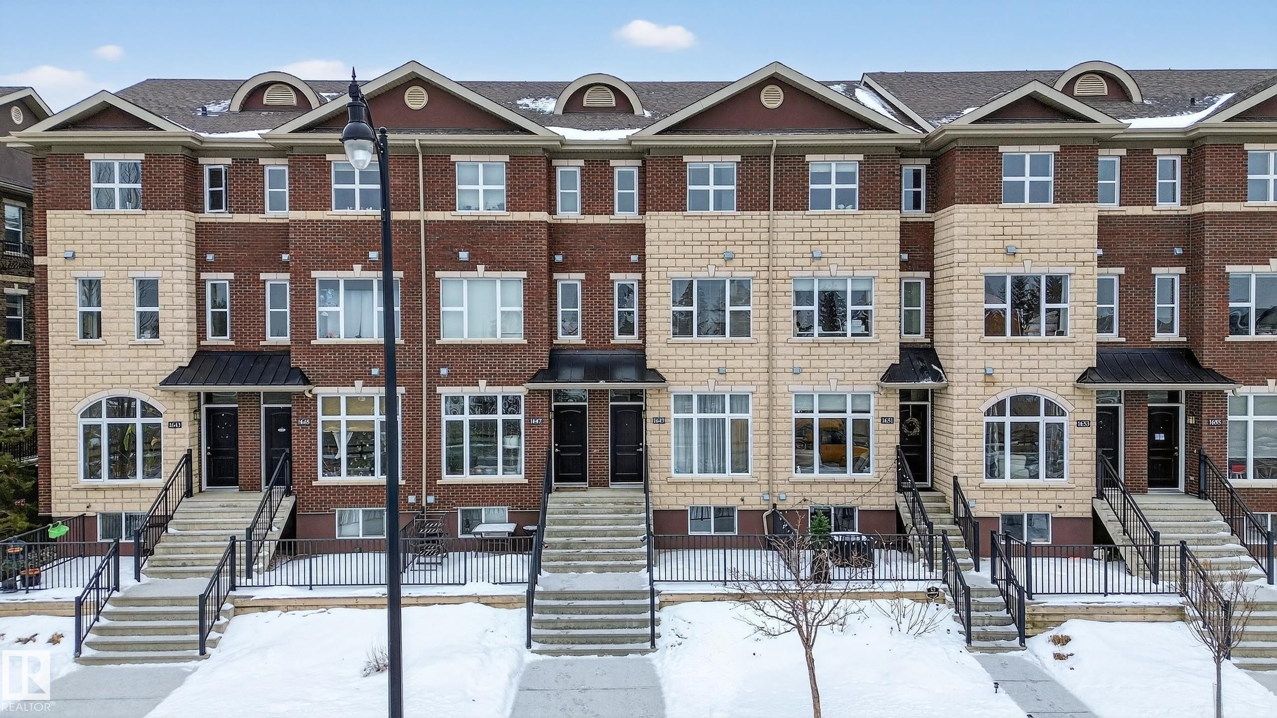 This property features a brick and stone facade with dark framed windows - 1649 Cunningham Way, Edmonton, AB - Outdoor With Facade