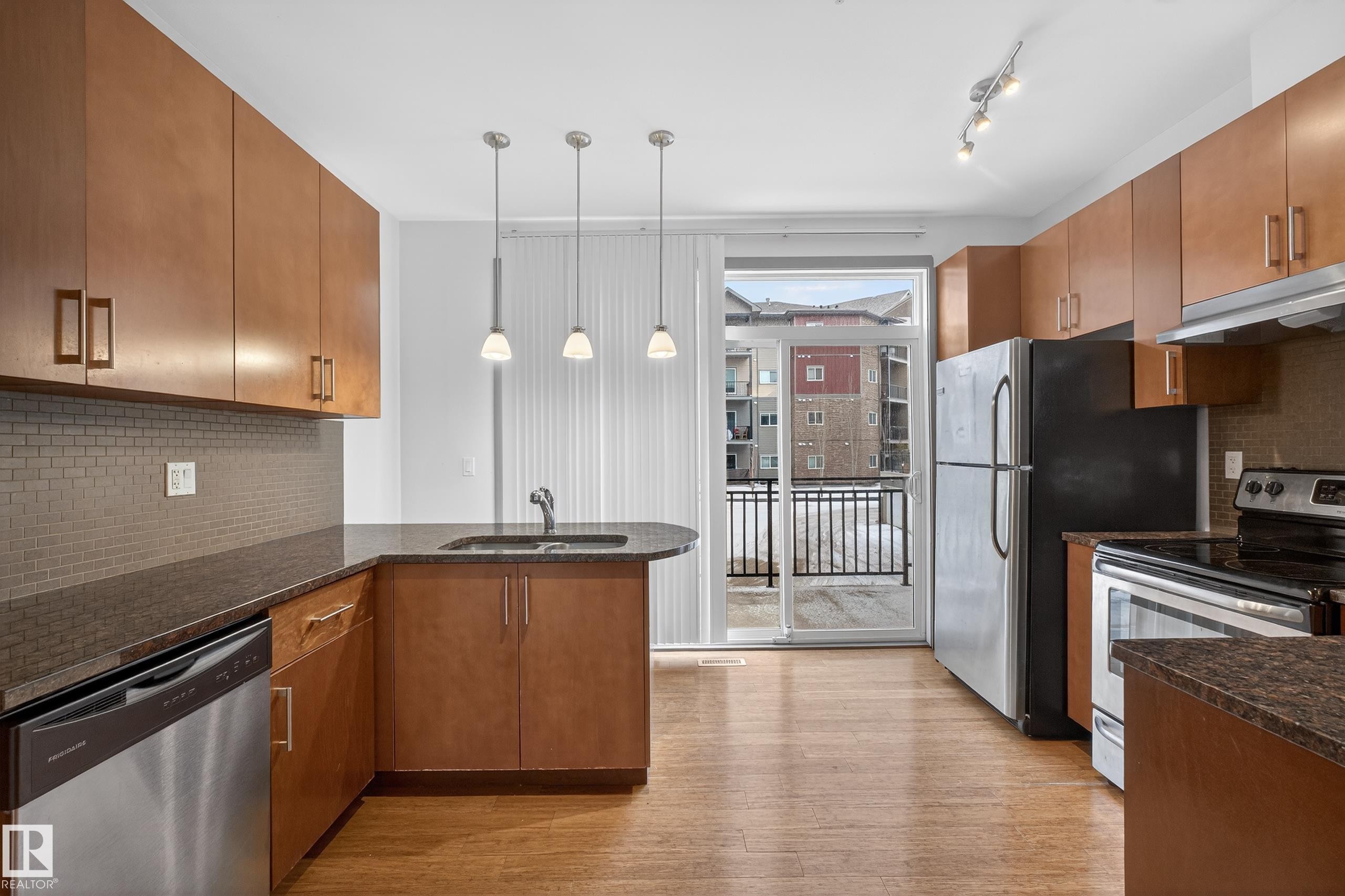 The kitchen features wood cabinetry, a tiled backsplash, and stainless steel appliances including a refrigerator, dishwasher, and range - 1649 Cunningham Way, Edmonton, AB - Indoor Photo Showing Kitchen