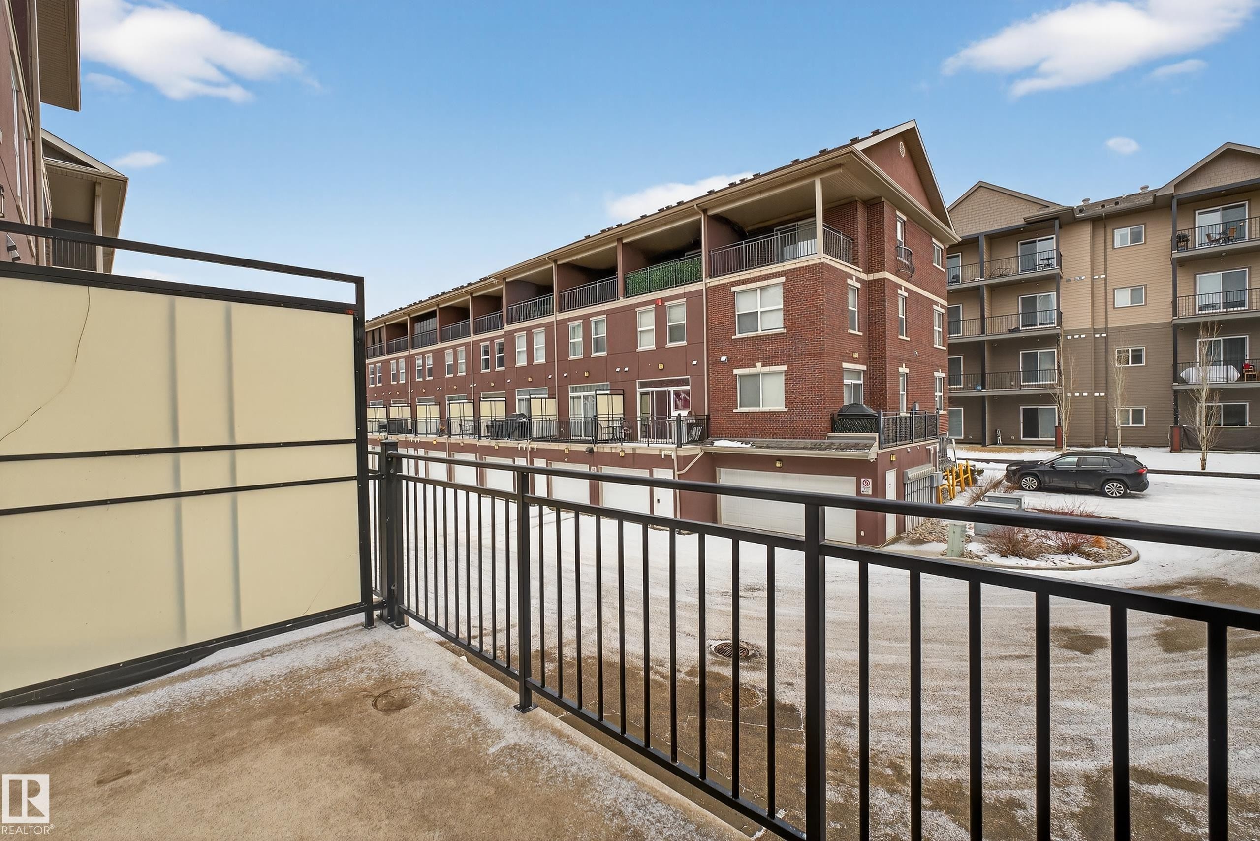 The property features a private balcony with a partial privacy screen and a black metal railing - 1649 Cunningham Way, Edmonton, AB - Outdoor With Balcony
