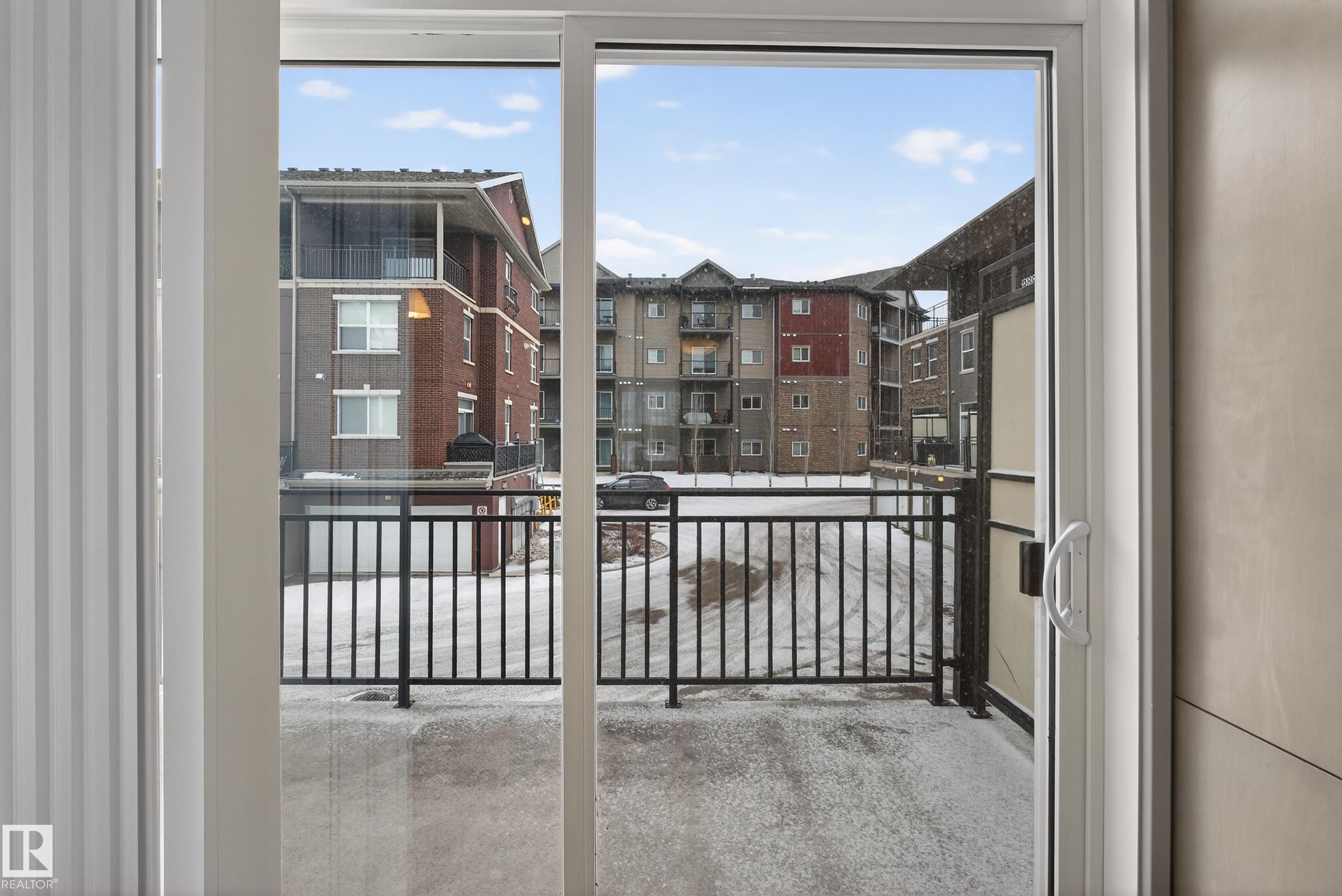 Sliding patio doors open to a private balcony with black metal railings - 1649 Cunningham Way, Edmonton, AB - Photo Showing Other Room