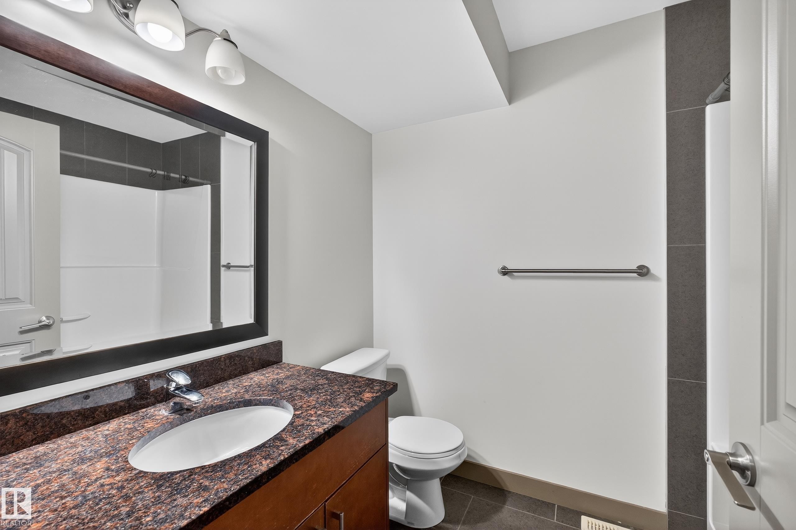 The bathroom features a vanity with a brown granite countertop and an oval sink, a wall-mounted mirror, and overhead lighting - 1649 Cunningham Way, Edmonton, AB - Indoor Photo Showing Bathroom