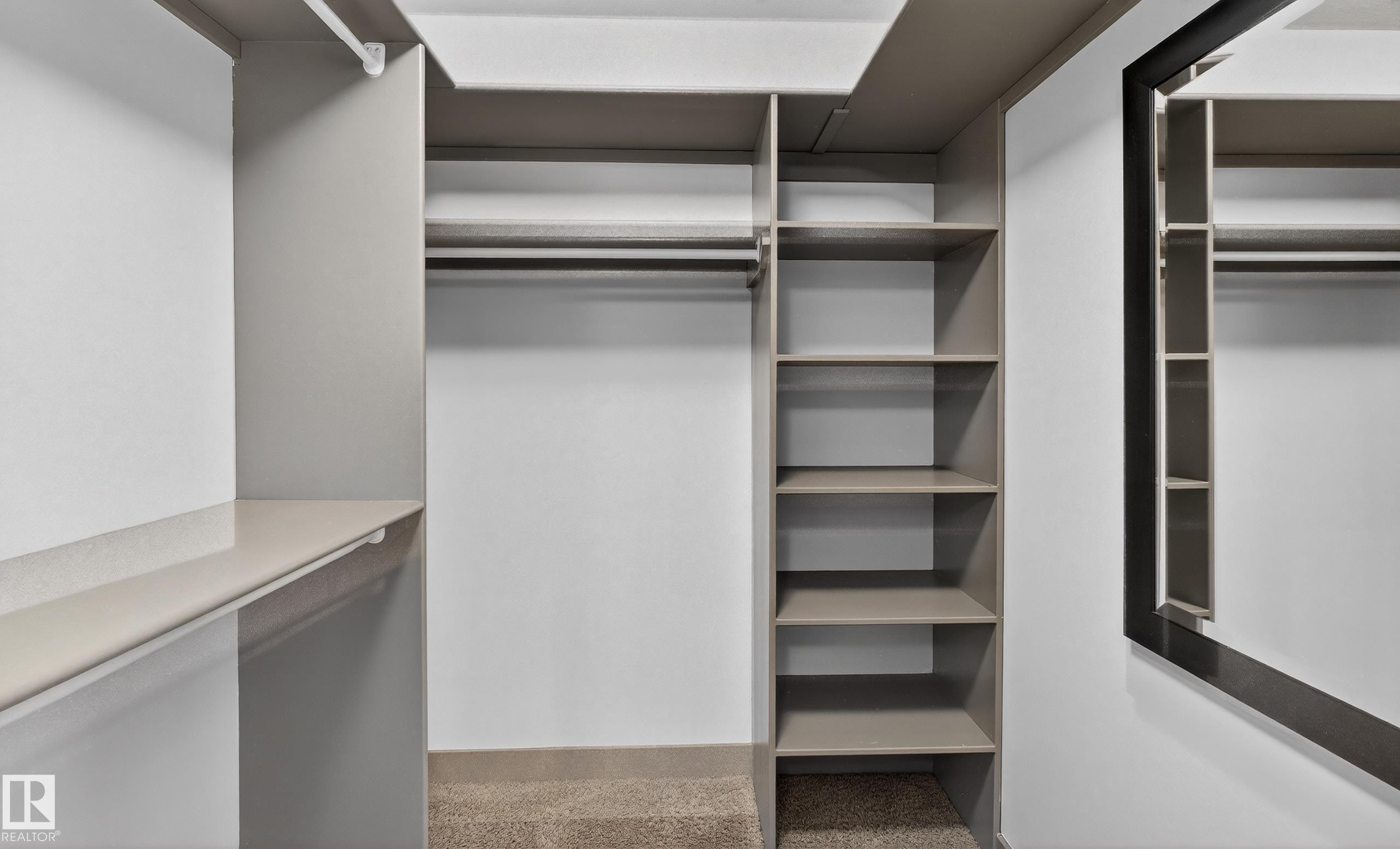 The closet features built-in shelving, hanging rods, and a full-length mirror - 1649 Cunningham Way, Edmonton, AB - Indoor With Storage