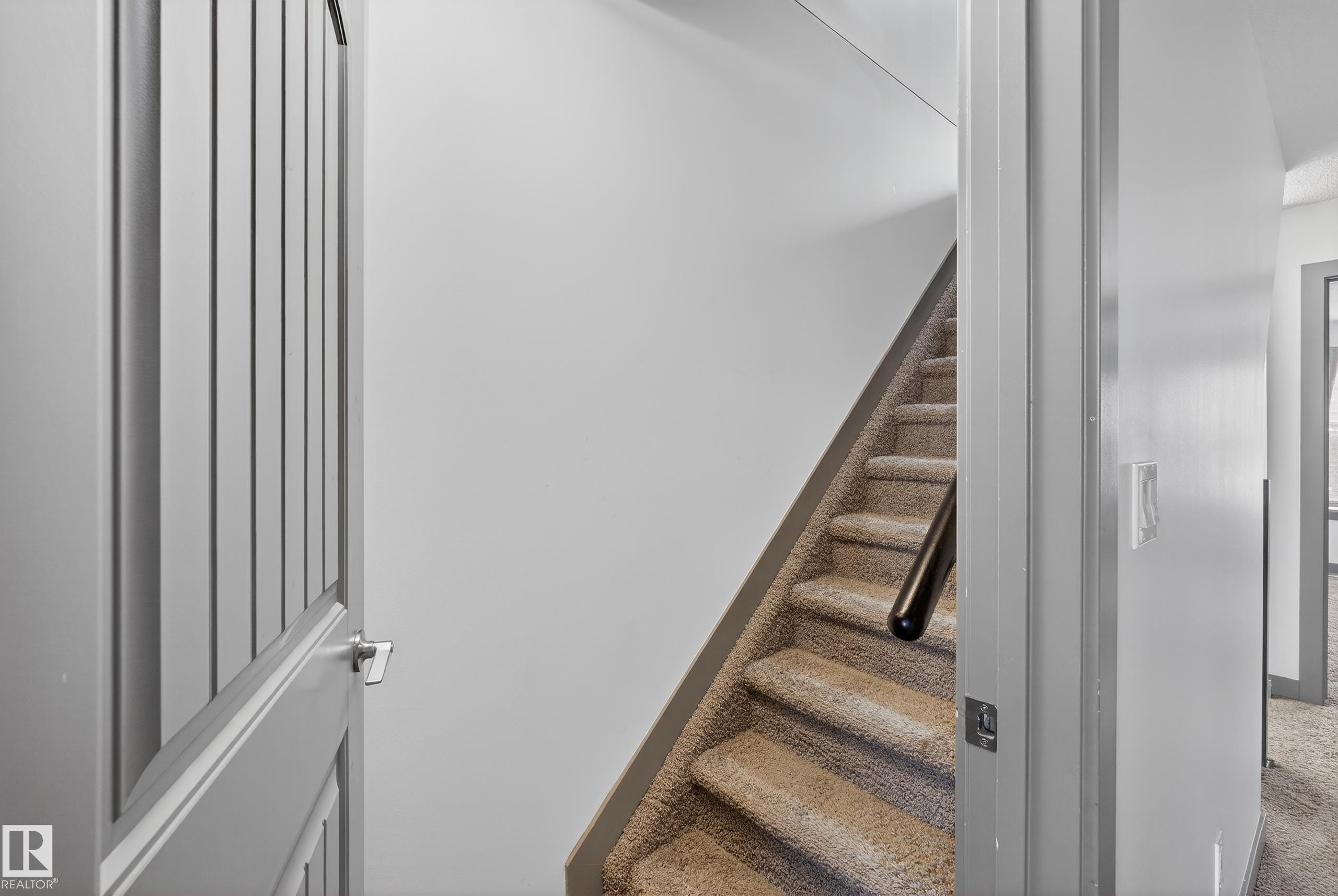 Carpeted staircase with a dark handrail, leading to an upper level - 1649 Cunningham Way, Edmonton, AB - Indoor Photo Showing Other Room