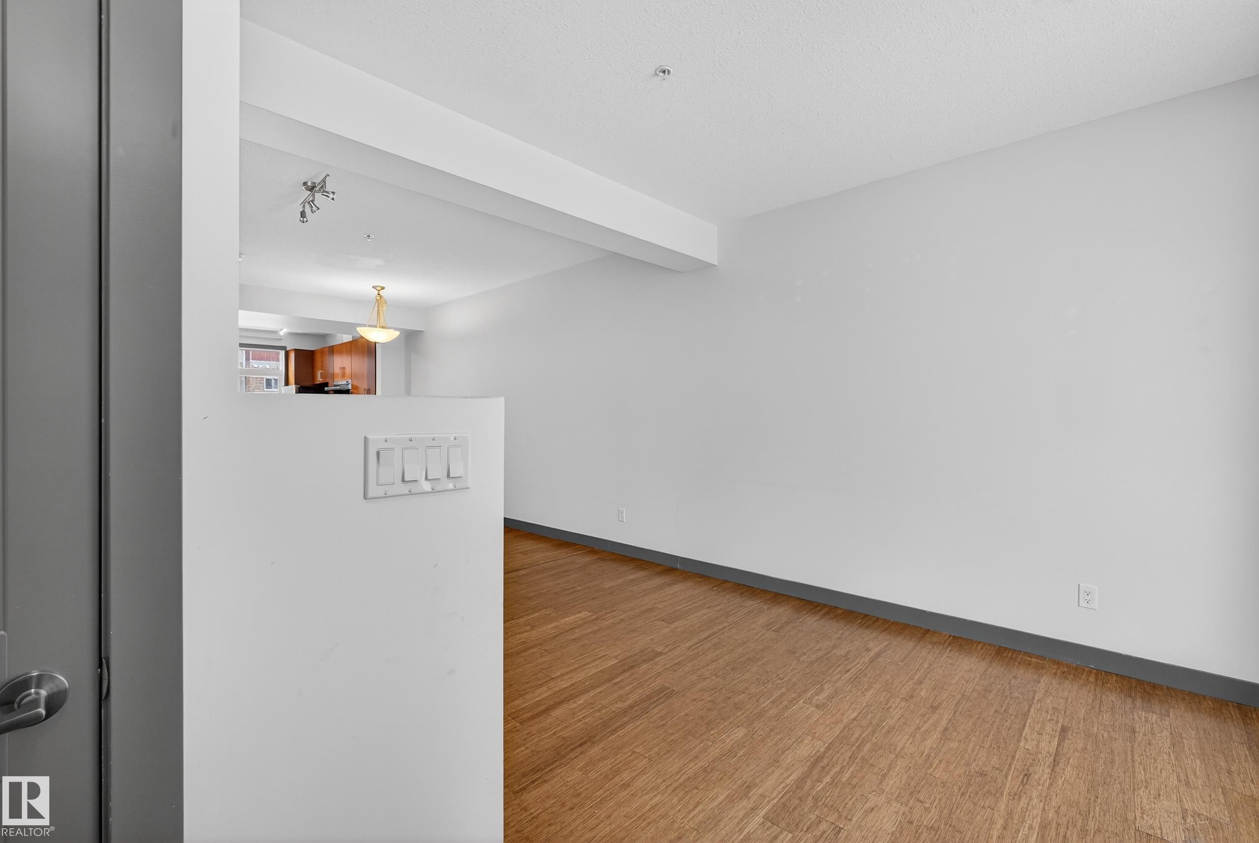 This room features hardwood flooring, white walls, and a view into a separate area with a chandelier - 1649 Cunningham Way, Edmonton, AB - Indoor Photo Showing Other Room