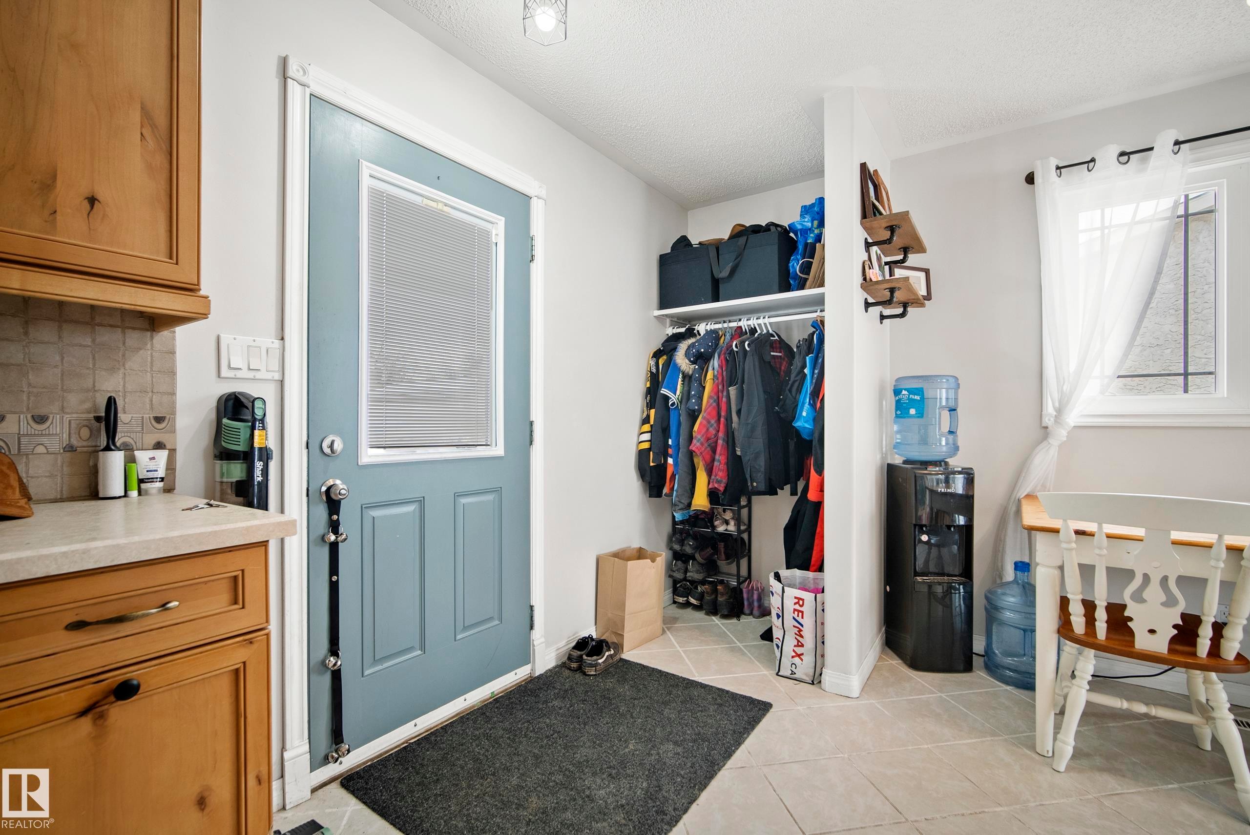 Laundry area with light tile patterned floors and a textured ceiling - 9221 84 Street, Fort Saskatchewan, AB - Indoor