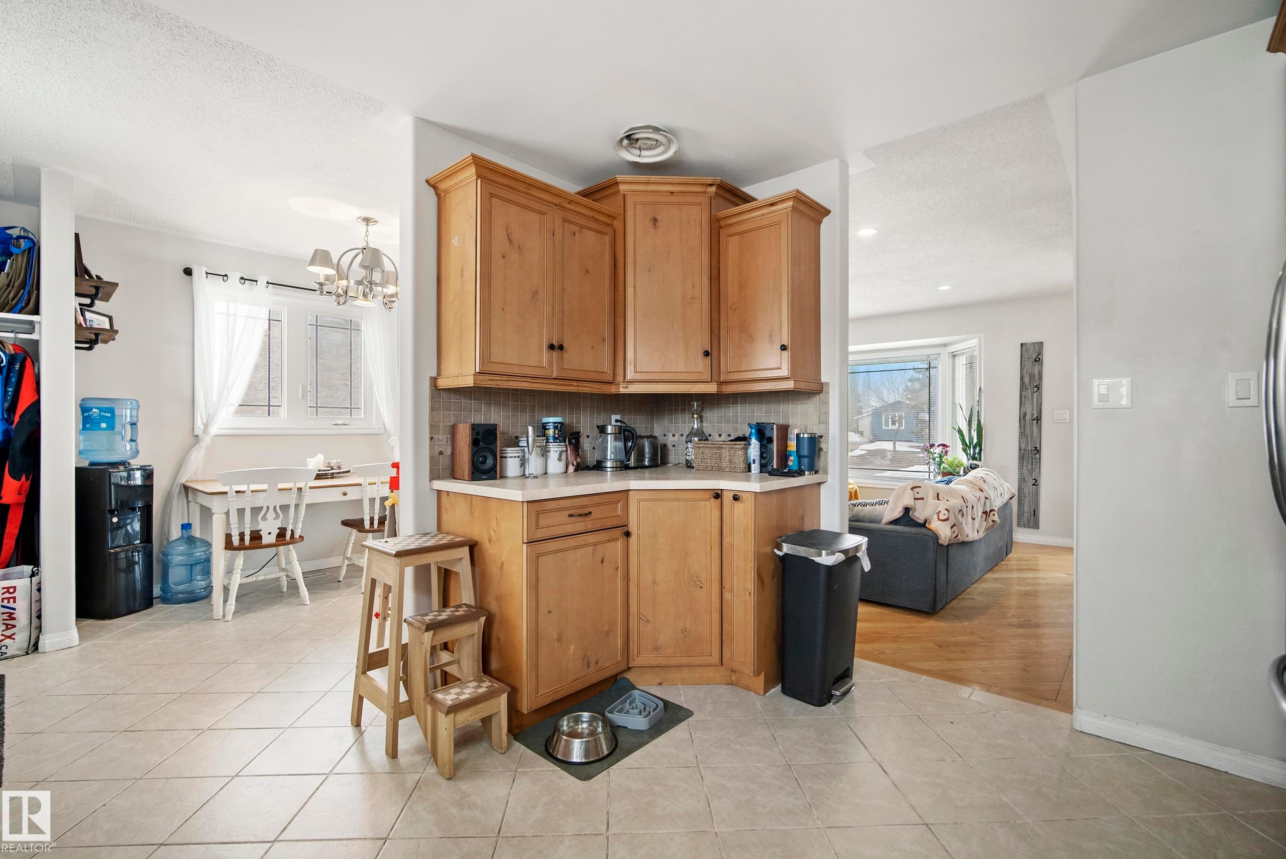 Kitchen with light countertops, light tile patterned floors, a chandelier, tasteful backsplash, and wood finish cabinets - 9221 84 Street, Fort Saskatchewan, AB - Indoor Photo Showing Other Room