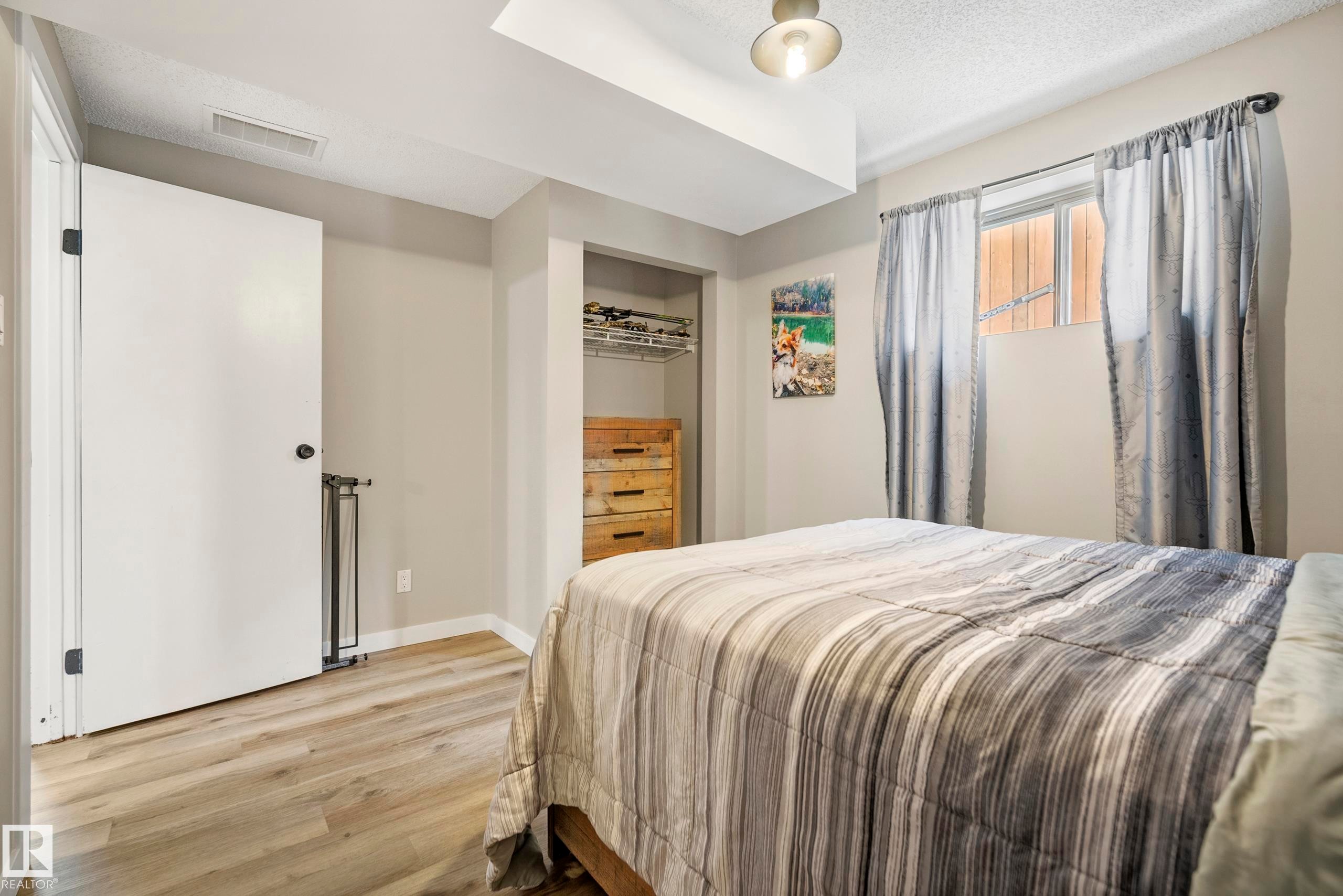 Bedroom with wood finished floors, a closet, and a textured ceiling - 9221 84 Street, Fort Saskatchewan, AB - Indoor Photo Showing Bedroom