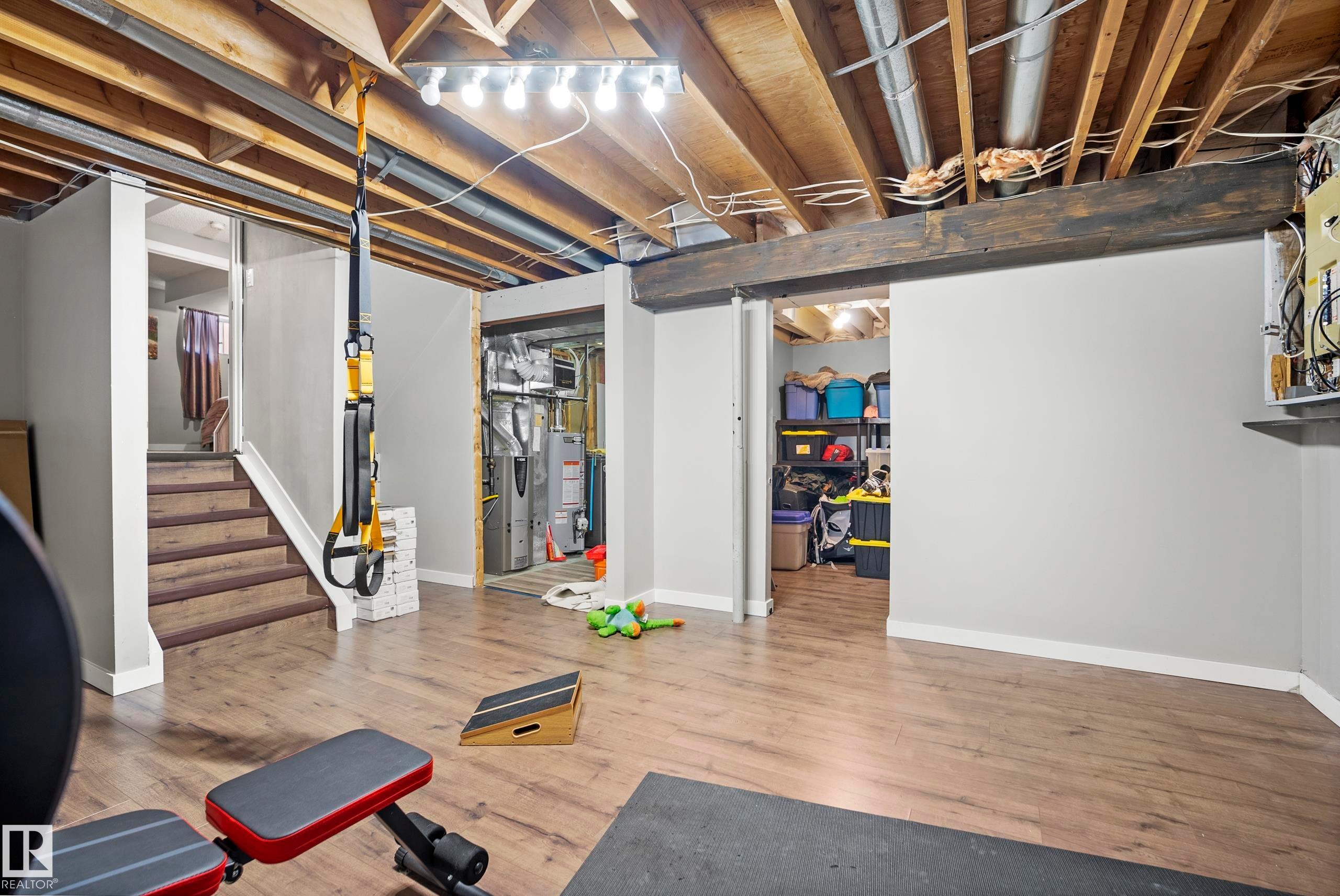 Unfinished below grade area featuring light wood-style flooring, gas water heater, and heating unit - 9221 84 Street, Fort Saskatchewan, AB - Indoor Photo Showing Basement