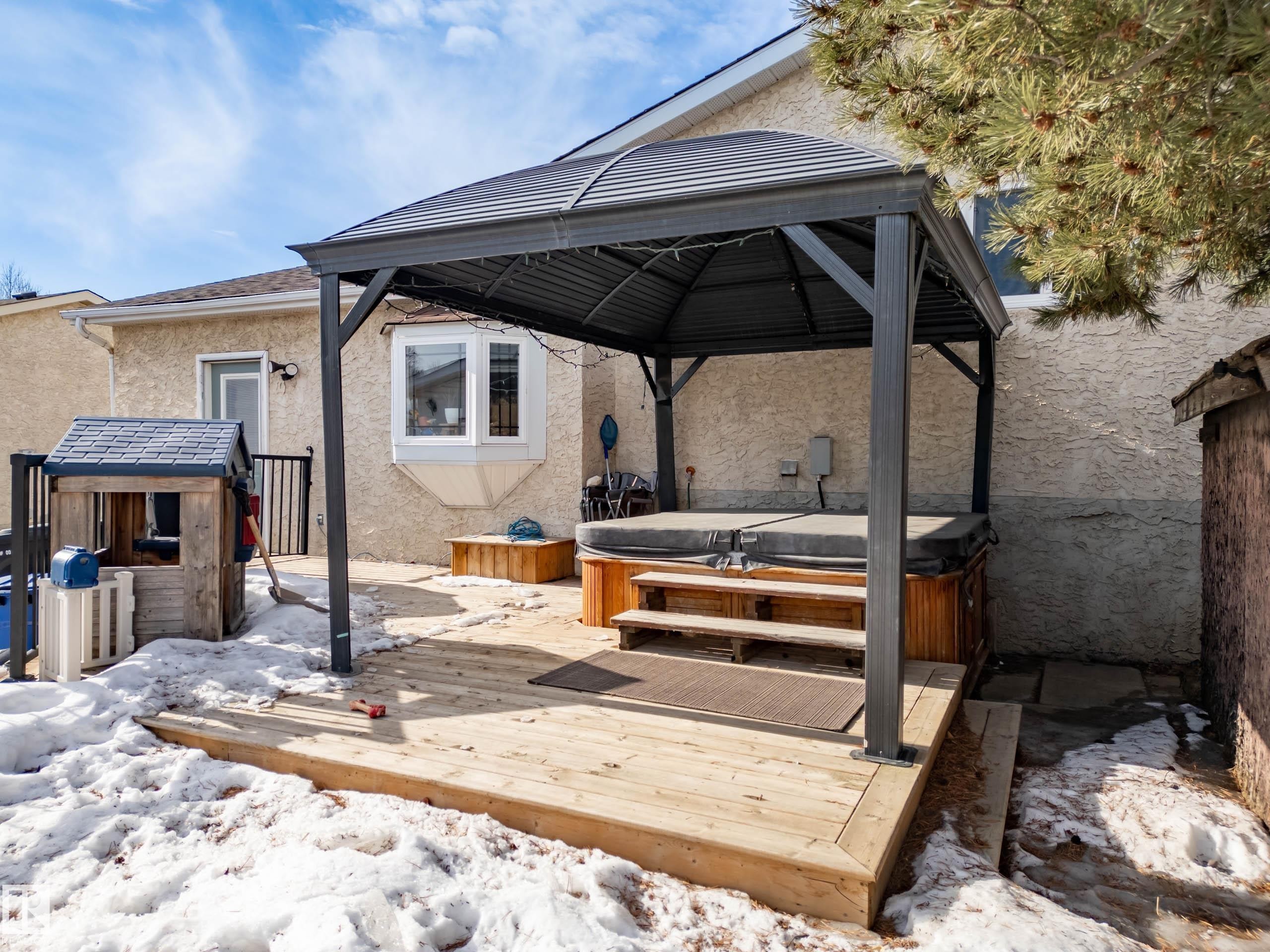 Snow covered patio featuring a gazebo, a hot tub, and a wooden deck - 9221 84 Street, Fort Saskatchewan, AB - Outdoor With Deck Patio Veranda With Exterior