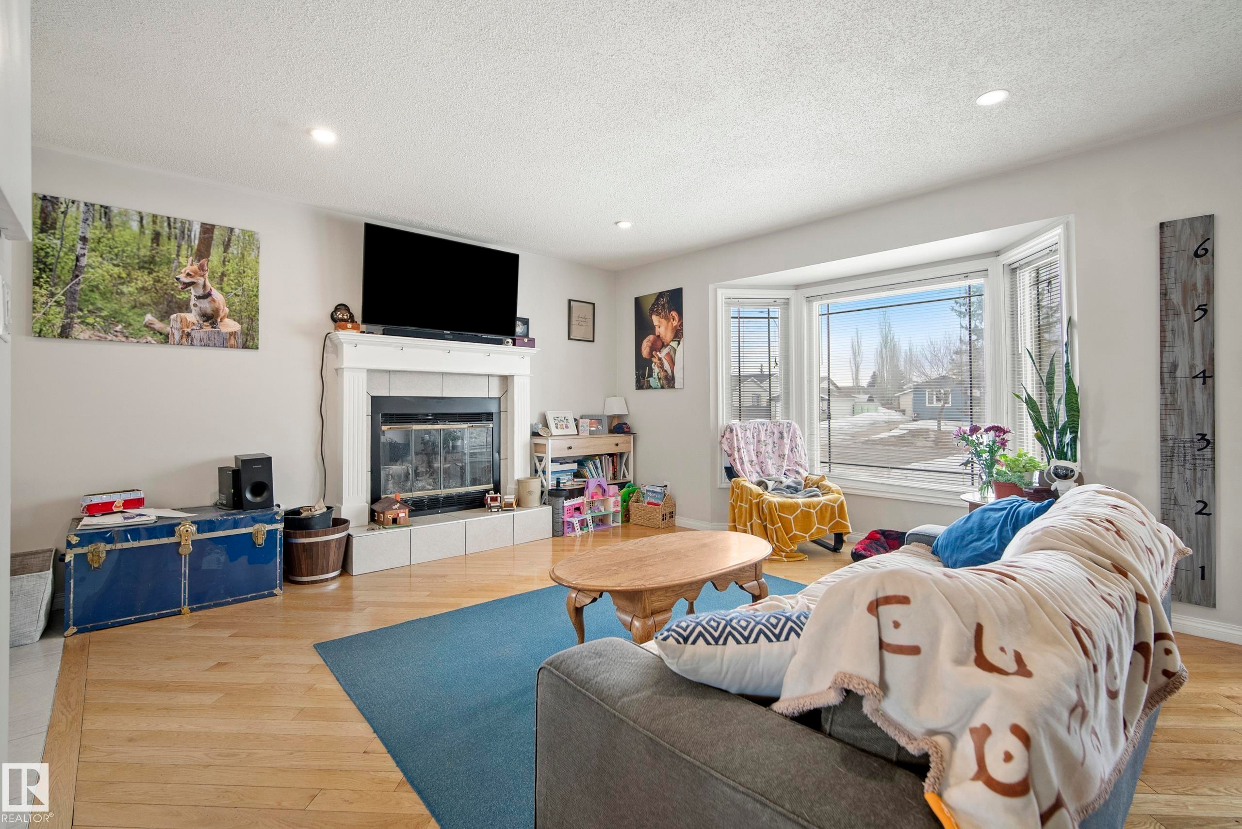 Living room featuring recessed lighting, light wood finished floors, a tile fireplace, and a textured ceiling - 9221 84 Street, Fort Saskatchewan, AB - Indoor Photo Showing Living Room With Fireplace