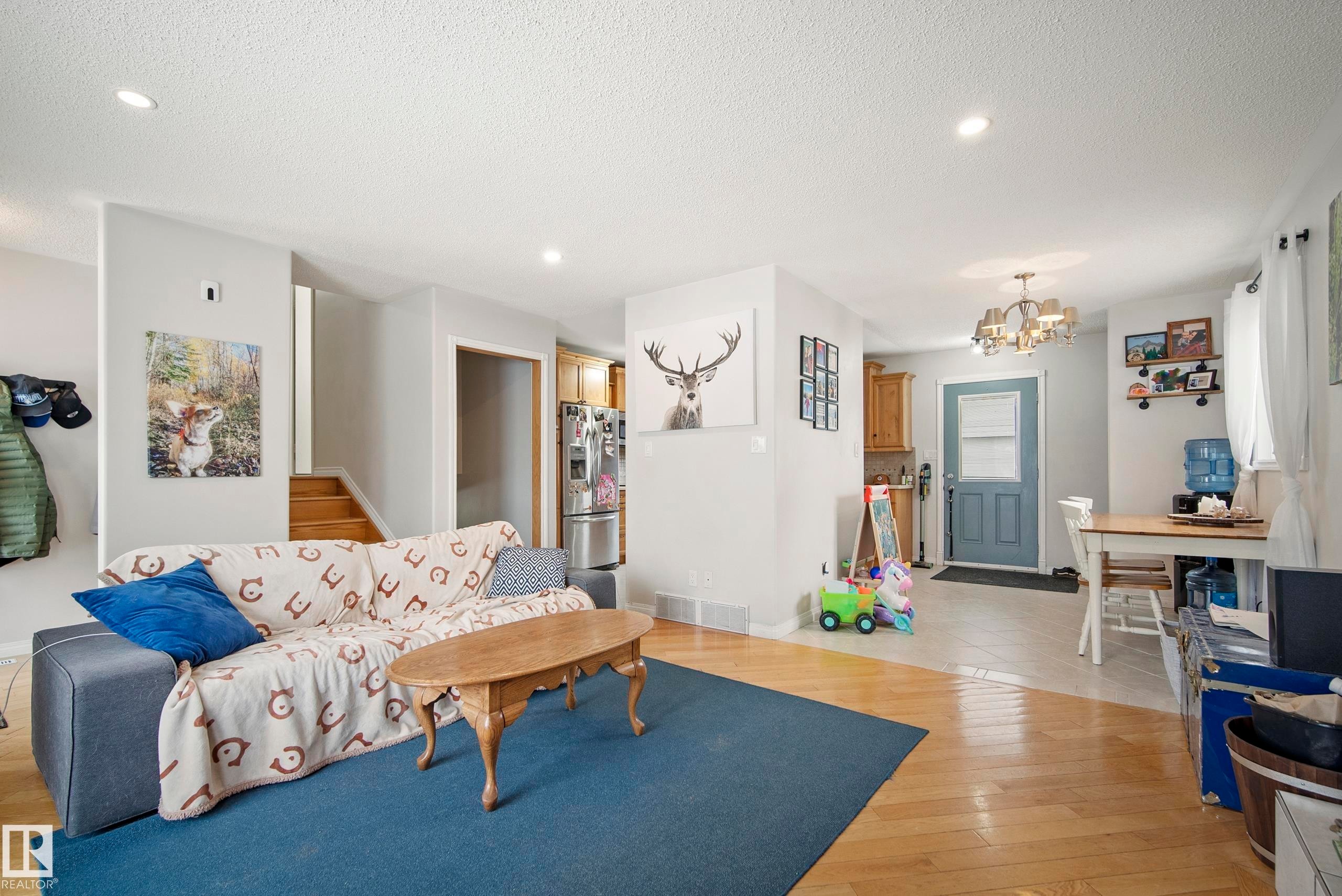 Living area featuring hanging lights, light wood-type flooring, and a textured ceiling - 9221 84 Street, Fort Saskatchewan, AB - Indoor Photo Showing Living Room