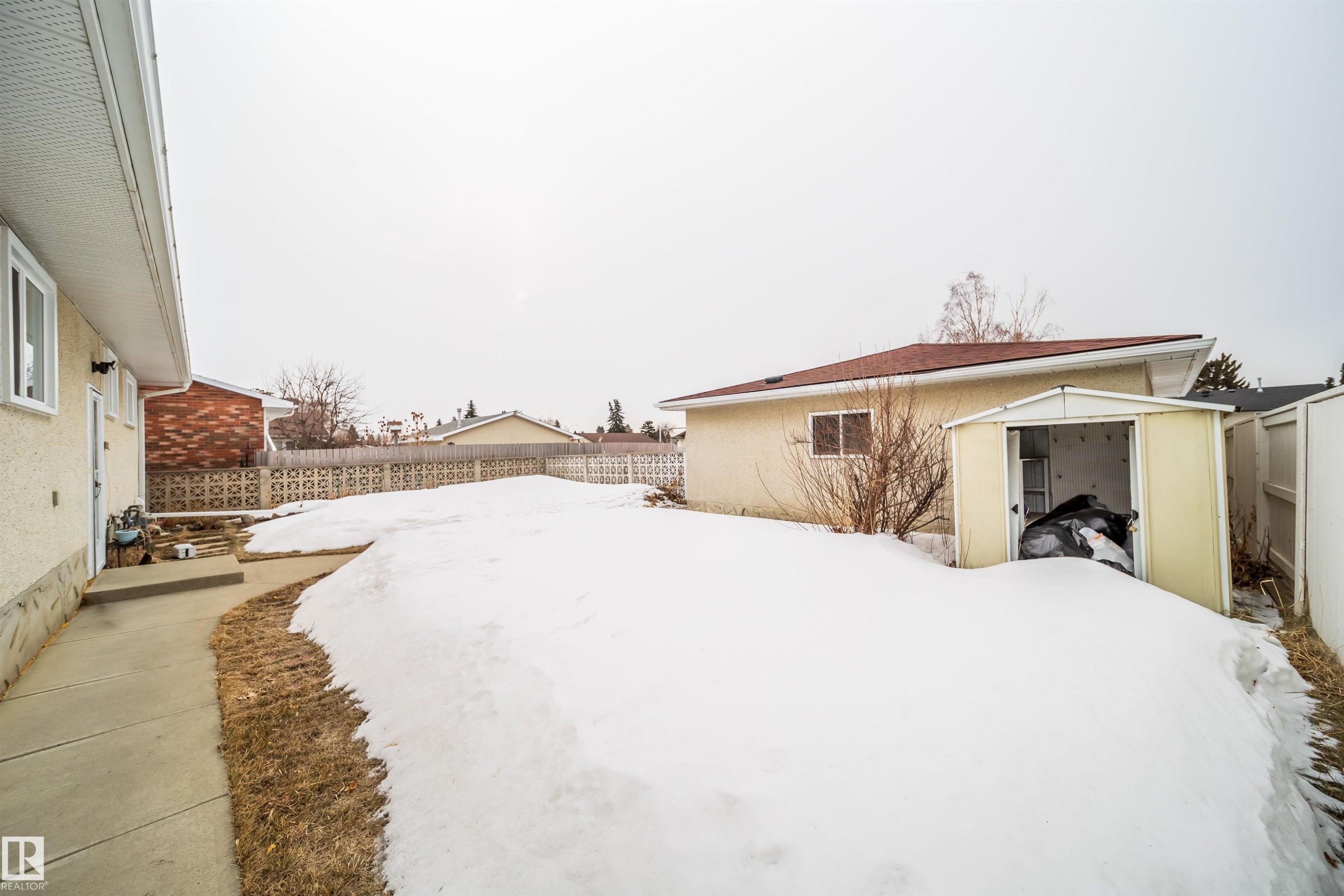 The property features a concrete walkway leading to an exterior door, a storage shed, and a fenced yard - 7911 145 Avenue Nw, Edmonton, AB - Outdoor With Exterior