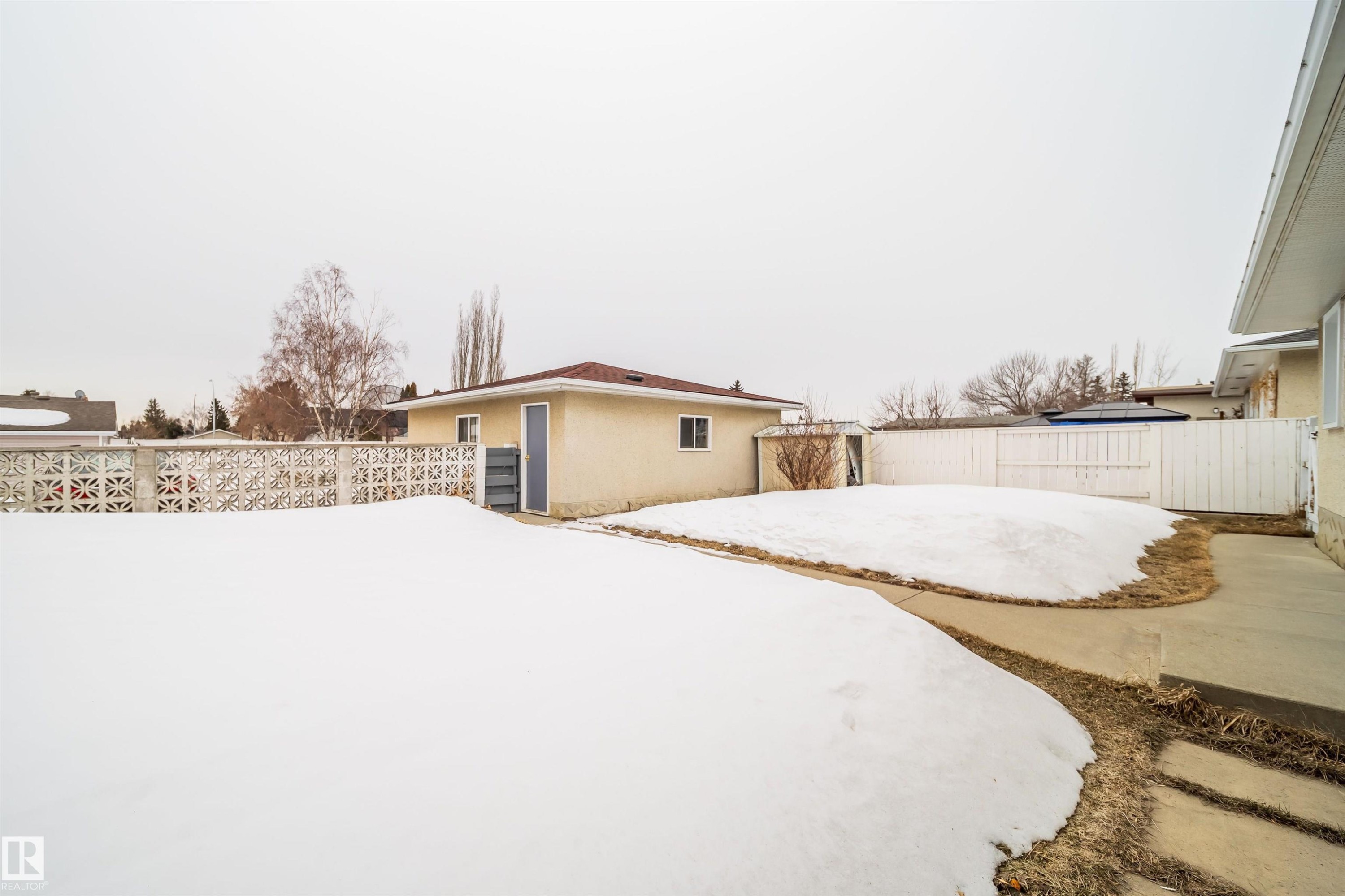 This property features an expansive yard with a concrete pathway and a detached structure - 7911 145 Avenue Nw, Edmonton, AB - Outdoor