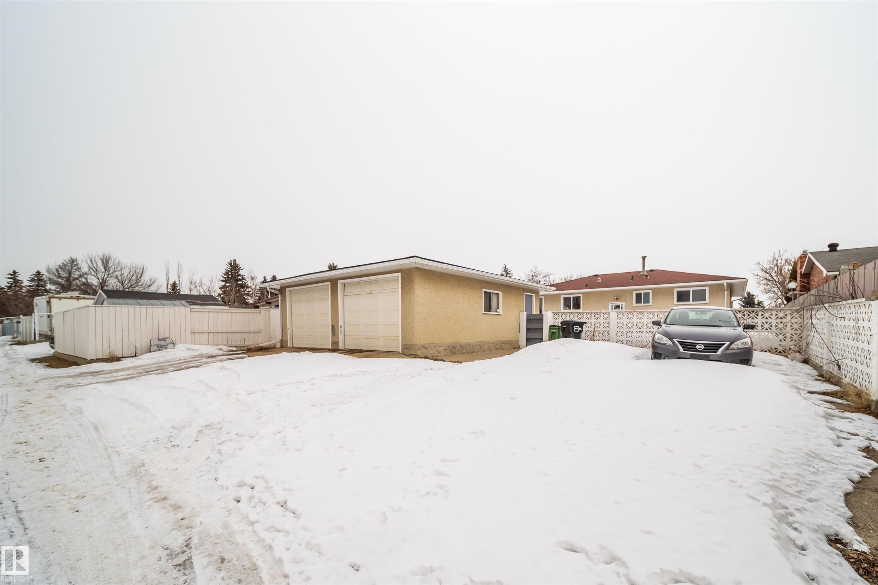 The property features a detached garage with two garage doors and a paved driveway - 7911 145 Avenue Nw, Edmonton, AB - Outdoor