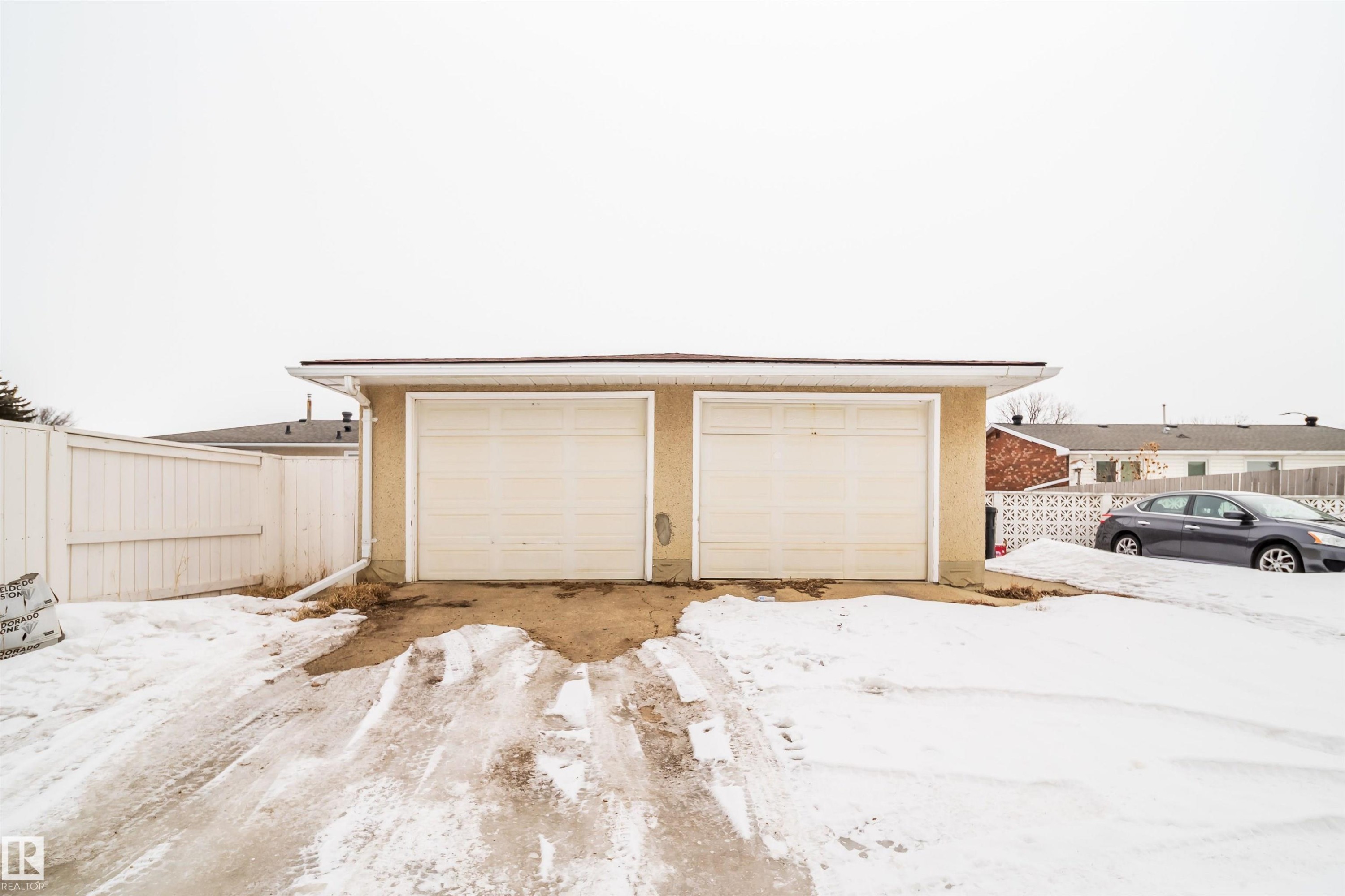 Detached garage with two garage doors and a light-colored stucco exterior - 7911 145 Avenue Nw, Edmonton, AB - Outdoor With Exterior
