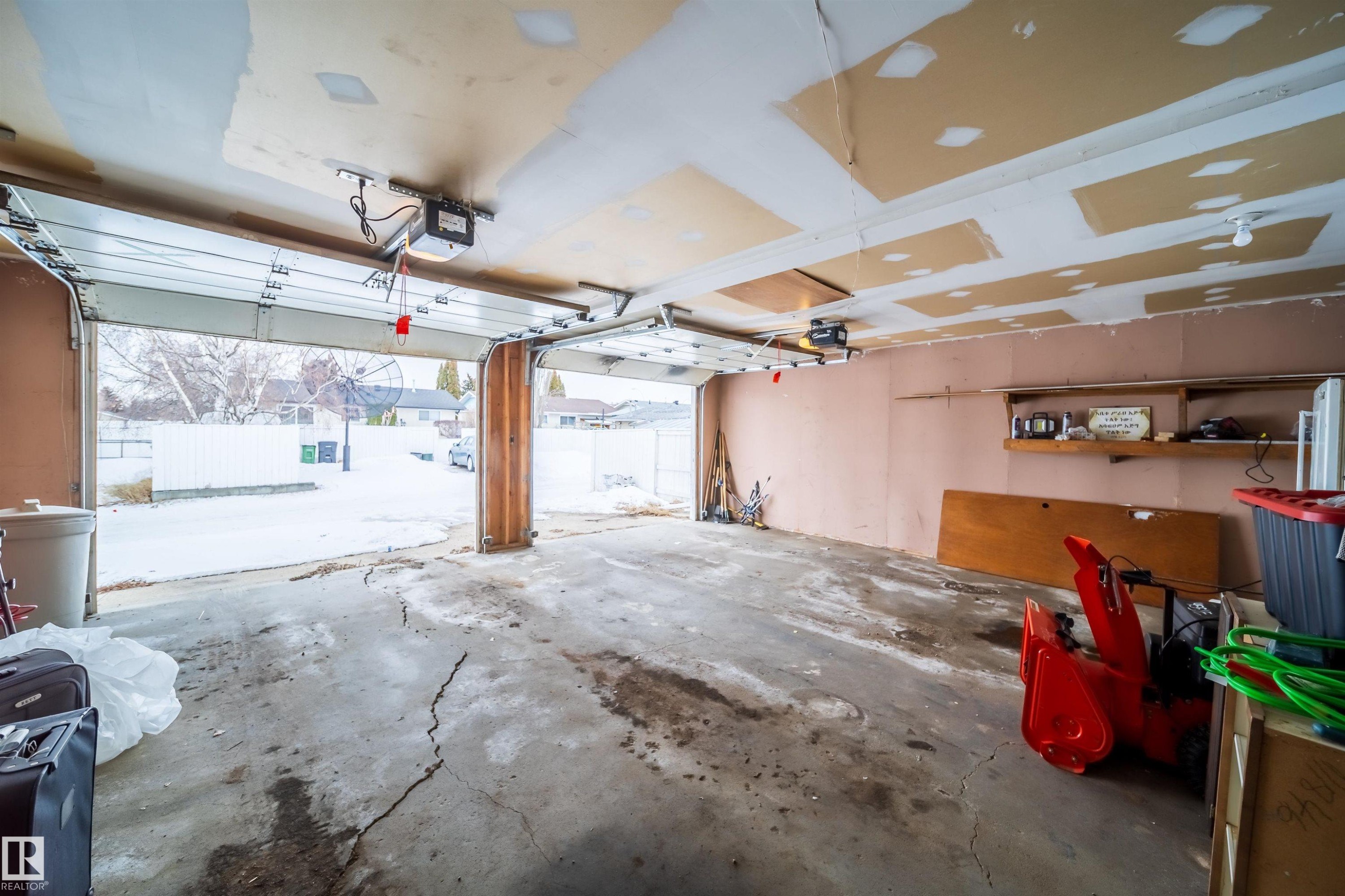 The property features a two-car garage with overhead doors and an exposed ceiling - 7911 145 Avenue Nw, Edmonton, AB - Indoor Photo Showing Garage