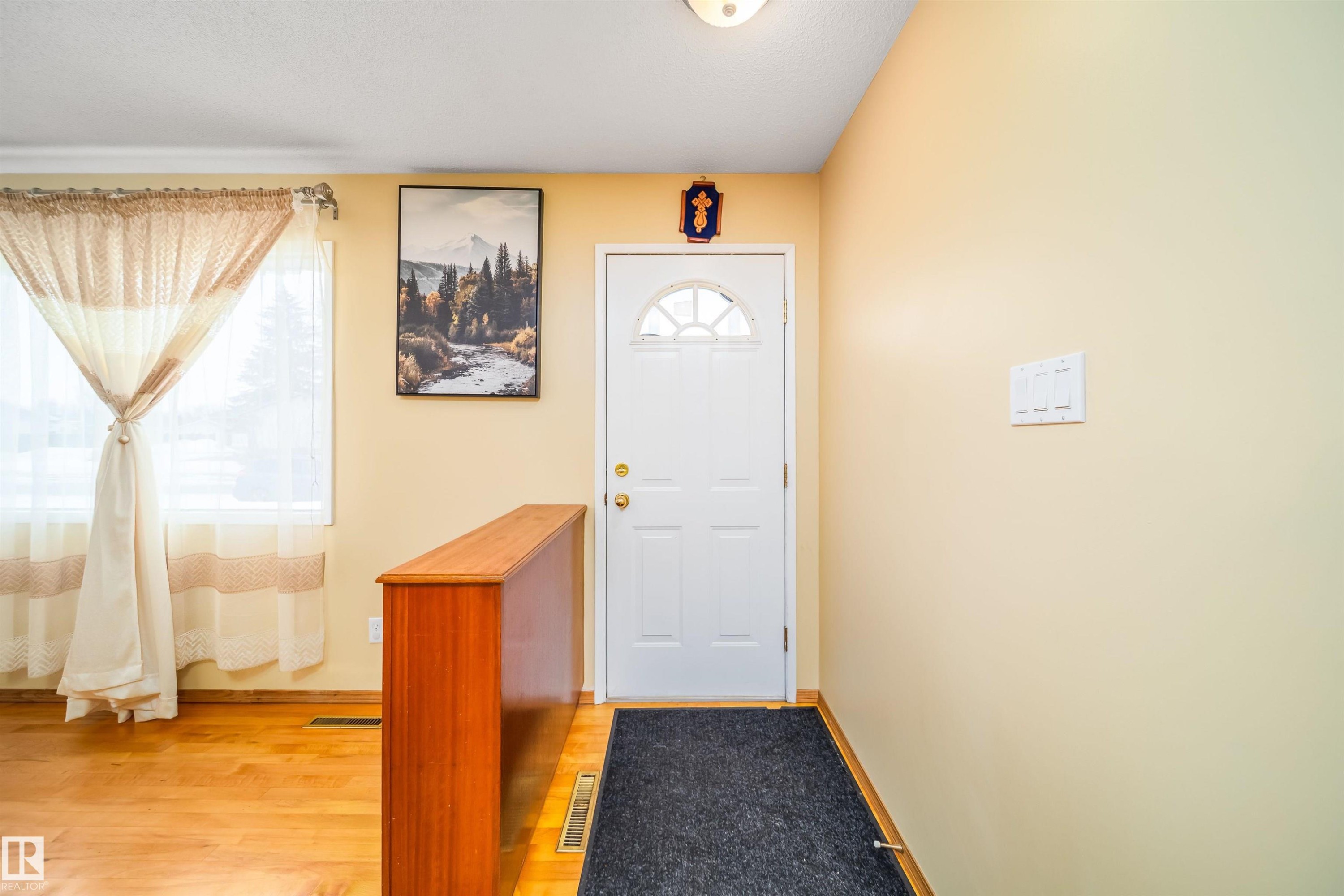 Entryway featuring a white door with an arched window, light-colored walls, and hardwood flooring - 7911 145 Avenue Nw, Edmonton, AB - Indoor Photo Showing Other Room