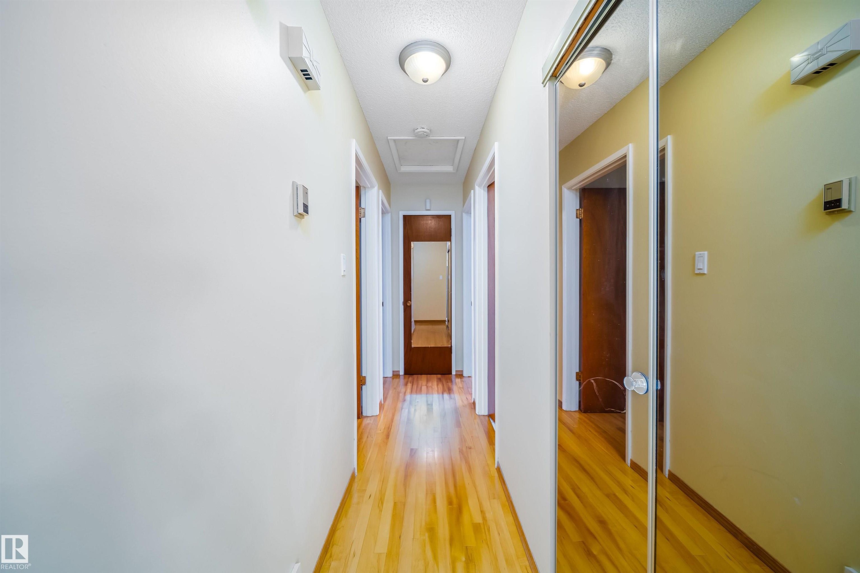 Hallway with hardwood flooring, light-toned walls, and flush mount ceiling lights - 7911 145 Avenue Nw, Edmonton, AB - Indoor Photo Showing Other Room