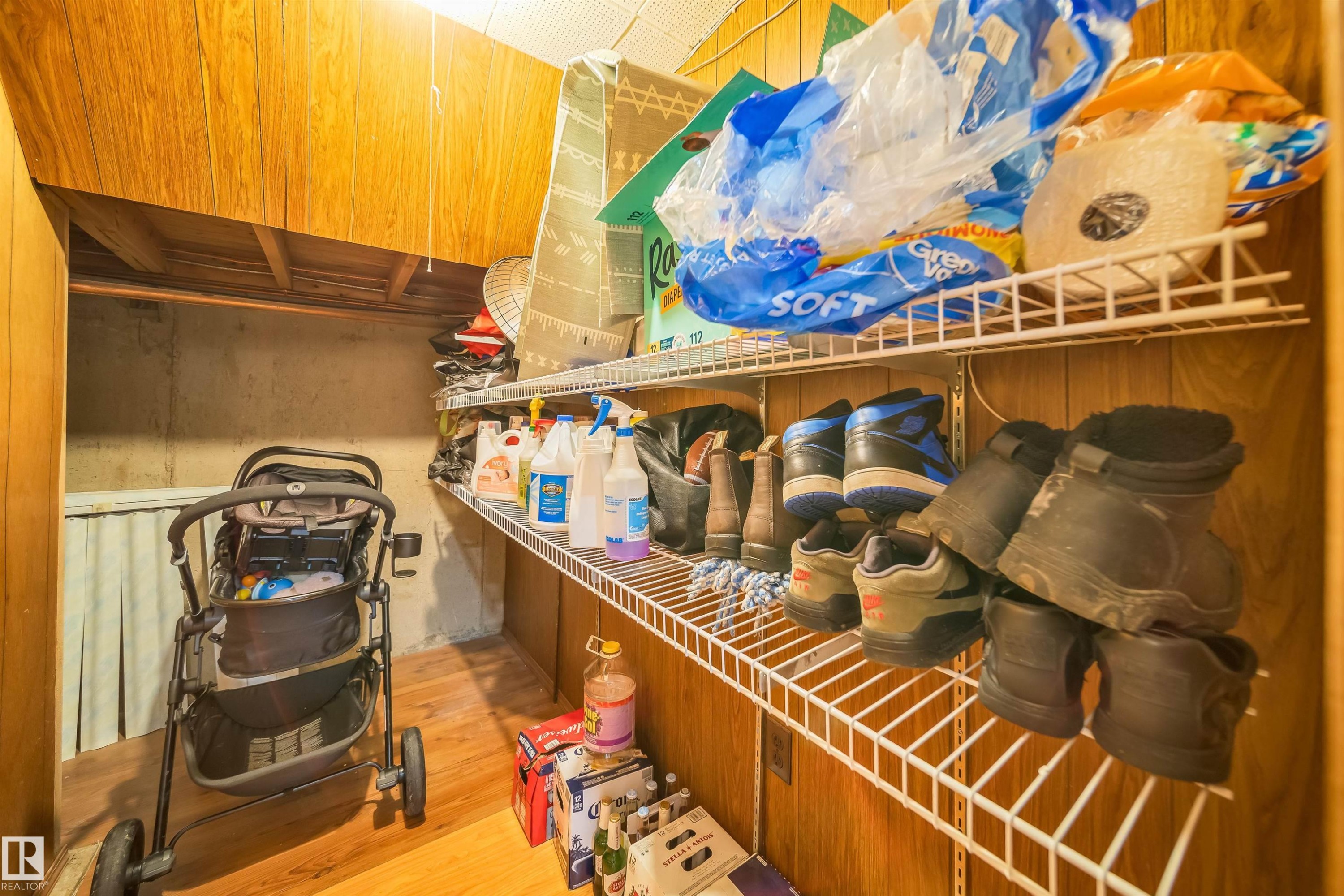 The property features a storage area with wood paneling, wire shelving, and wood flooring - 7911 145 Avenue Nw, Edmonton, AB - Indoor