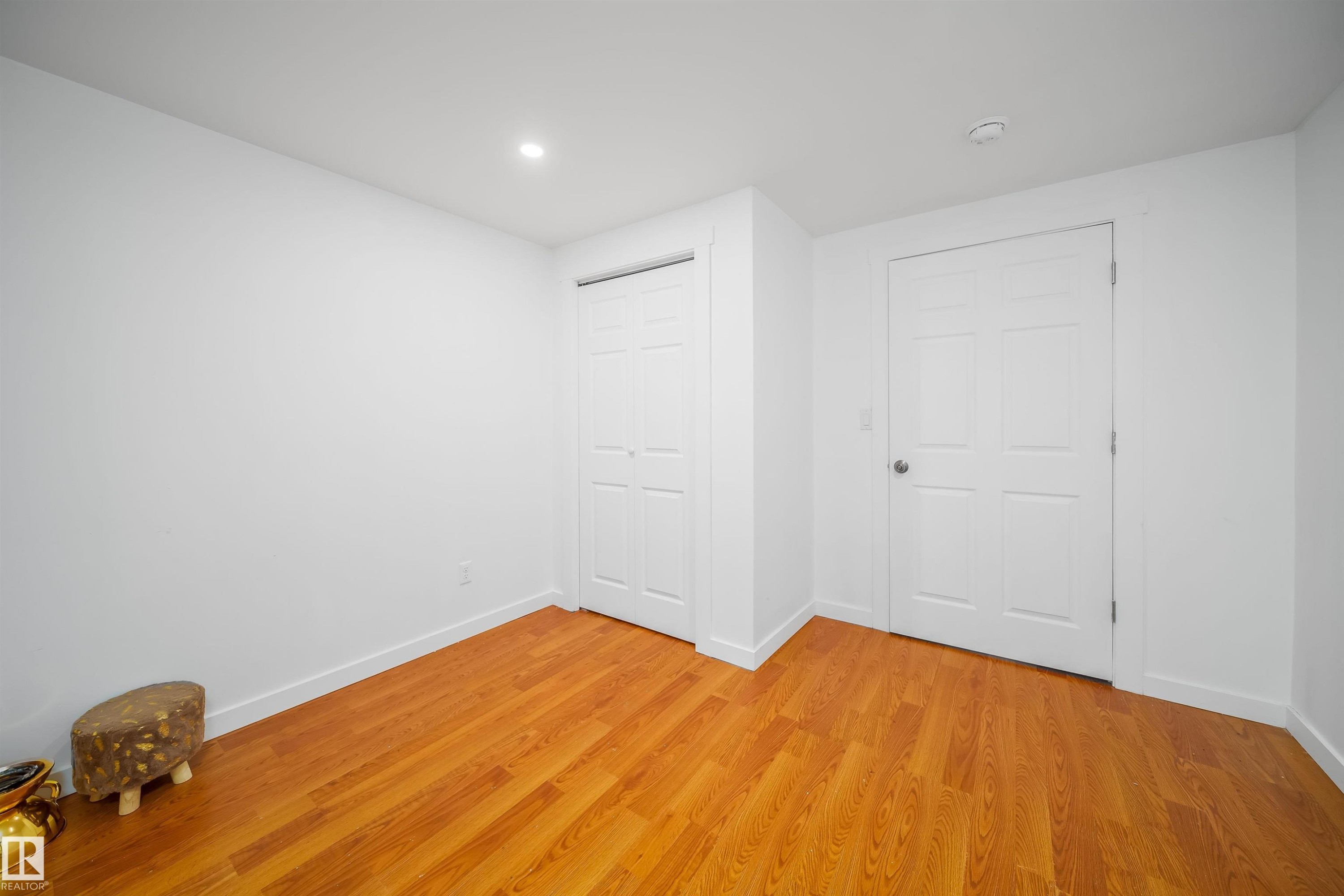 This room features hardwood flooring and white walls, with two white doors - 7911 145 Avenue Nw, Edmonton, AB - Indoor Photo Showing Other Room