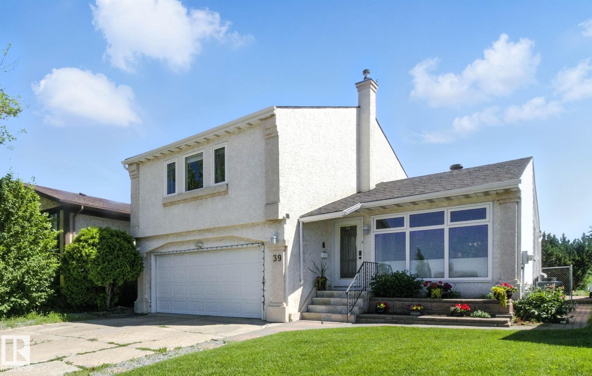 View of front facade featuring a garage, stucco siding, a chimney, concrete driveway, and a front yard - 39 Grand Meadow Crescent, Edmonton, AB - Outdoor