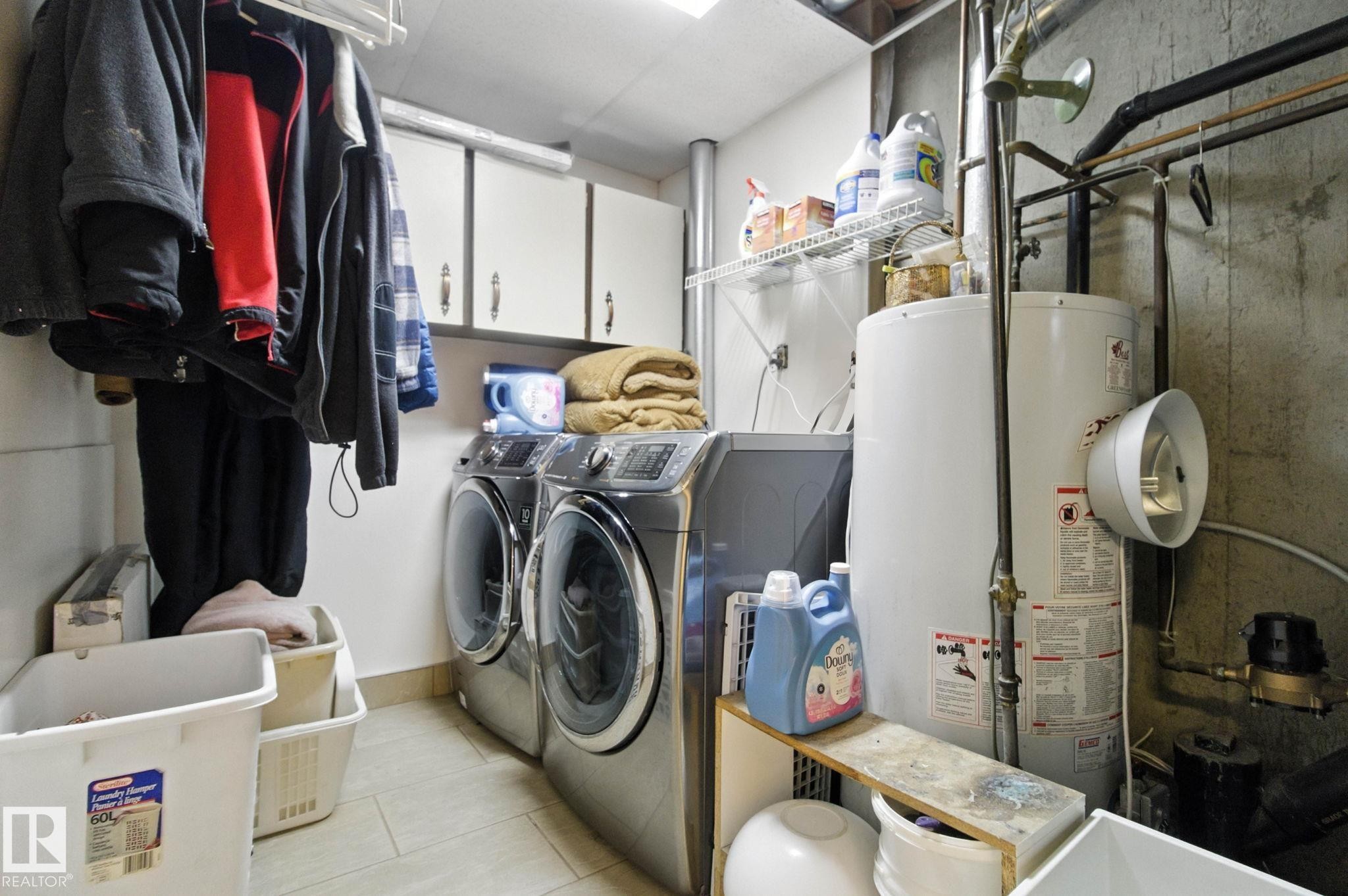 Laundry room with gas water heater, cabinet space, separate washer and dryer, and light tile patterned floors - 39 Grand Meadow Crescent, Edmonton, AB - Indoor Photo Showing Laundry Room