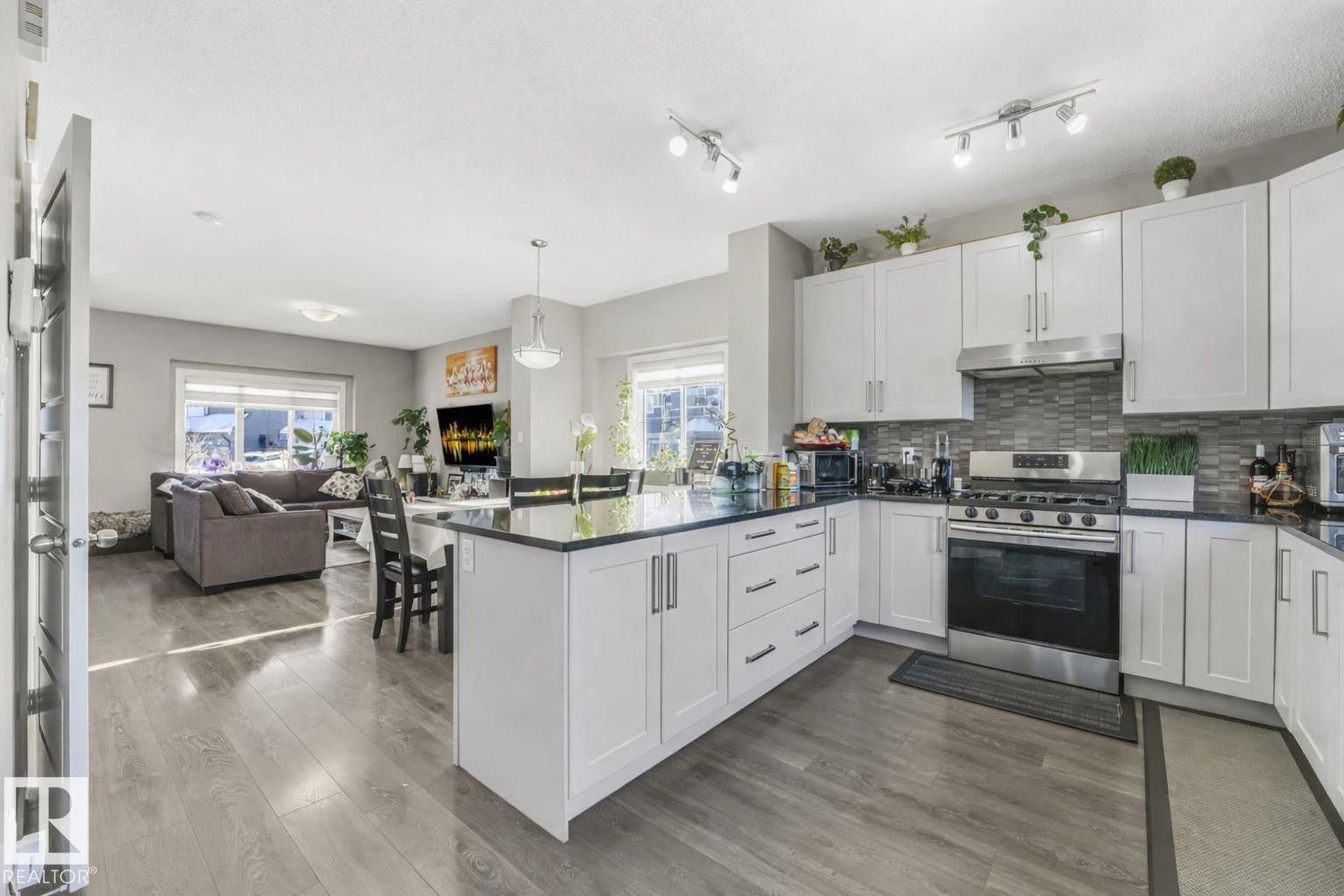 Kitchen featuring stainless steel range with gas cooktop, white cabinets, dark stone counters, and dark wood-style flooring - 2428 Wonnacott Crest, Edmonton, AB - Indoor Photo Showing Kitchen With Upgraded Kitchen