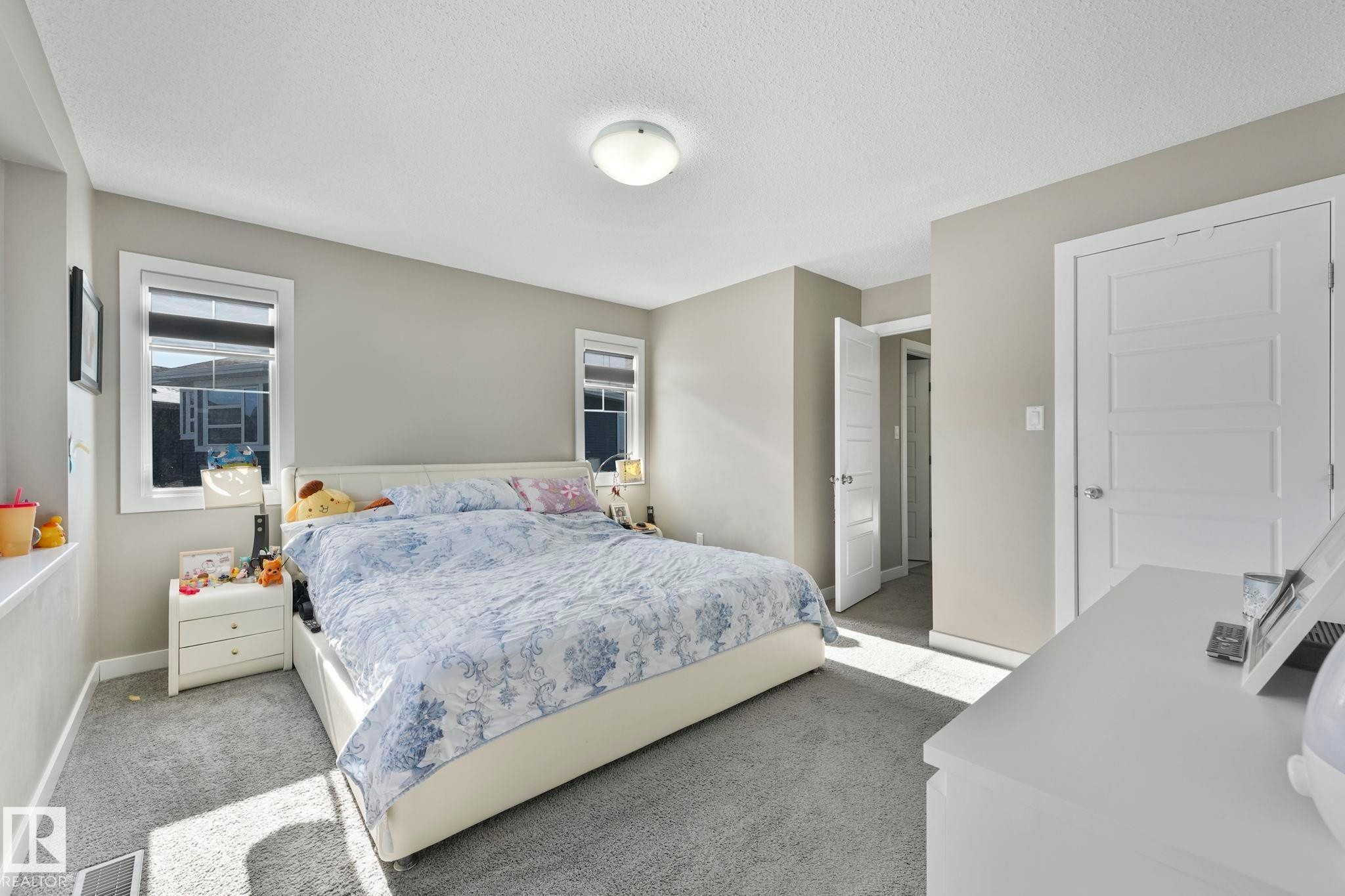 Carpeted bedroom with multiple windows and a textured ceiling - 2428 Wonnacott Crest, Edmonton, AB - Indoor Photo Showing Bedroom