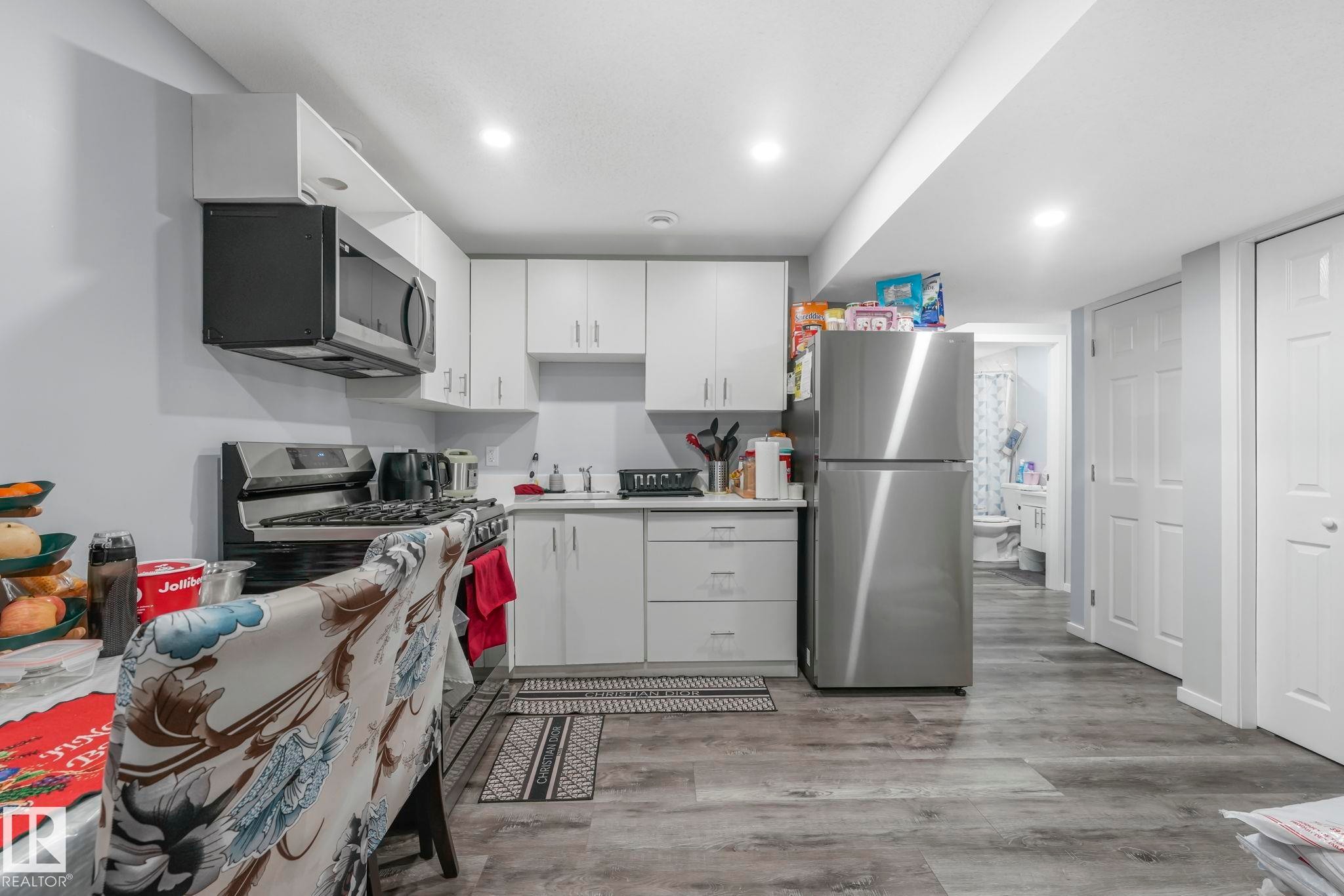 Kitchen featuring stainless steel appliances, light wood finished floors, light countertops, white cabinets, and recessed lighting - 2428 Wonnacott Crest, Edmonton, AB - Indoor Photo Showing Kitchen