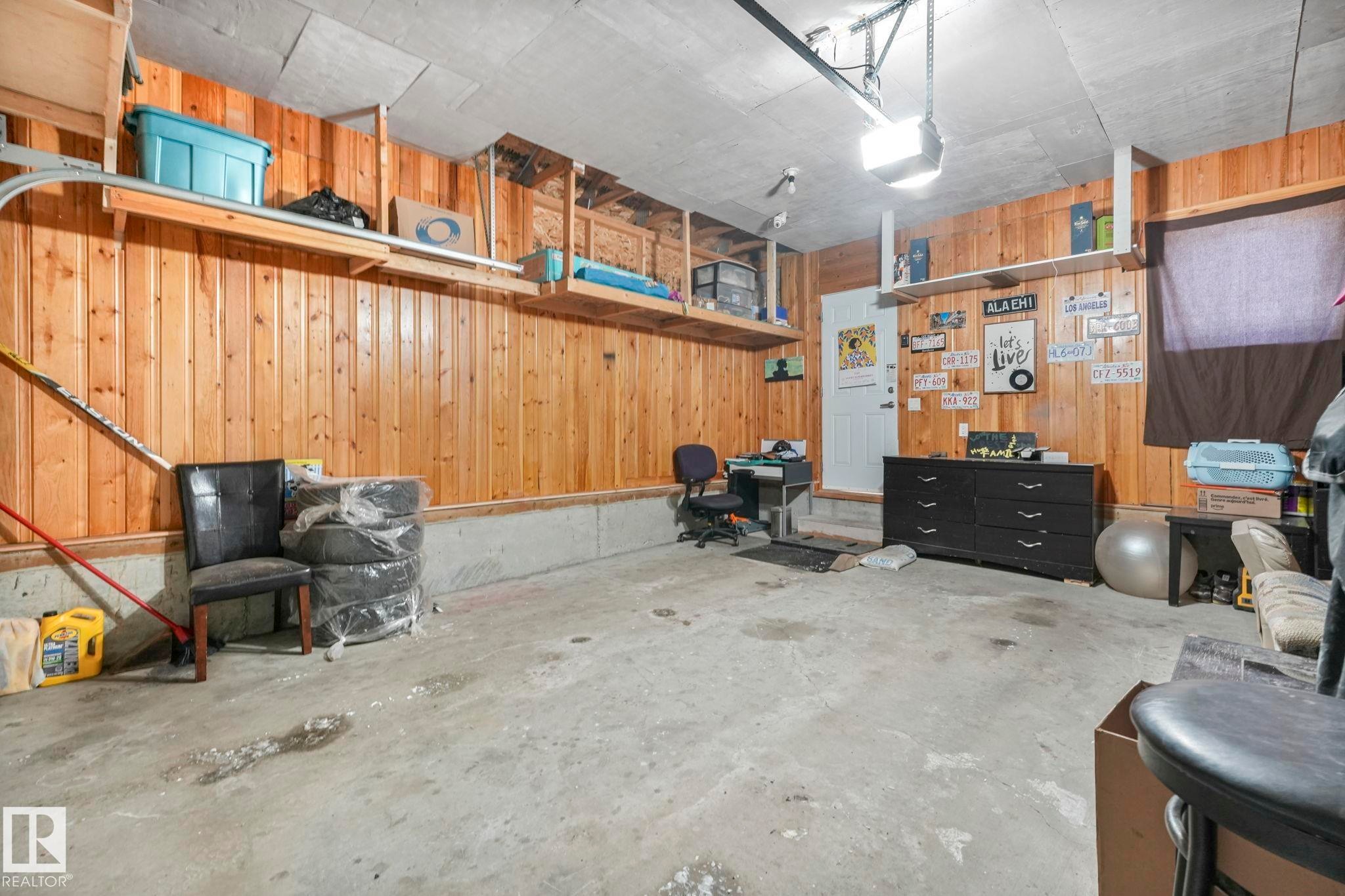 Garage featuring wood walls and a garage door opener - 2428 Wonnacott Crest, Edmonton, AB - Indoor Photo Showing Garage