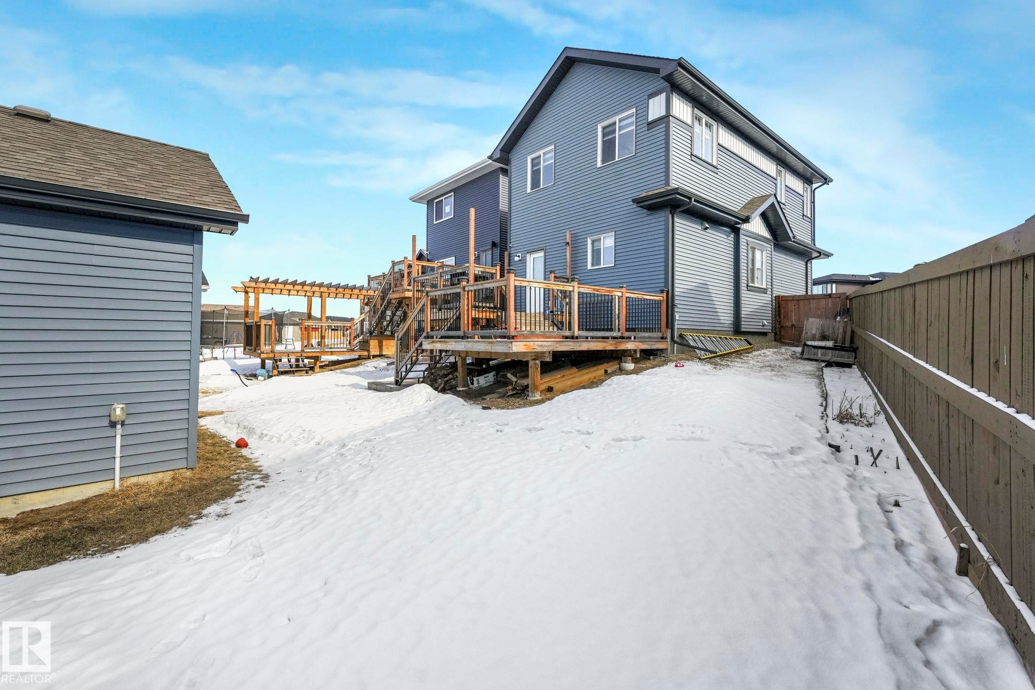 Snow covered house featuring a deck and a fenced backyard - 2428 Wonnacott Crest, Edmonton, AB - Outdoor With Deck Patio Veranda With Exterior