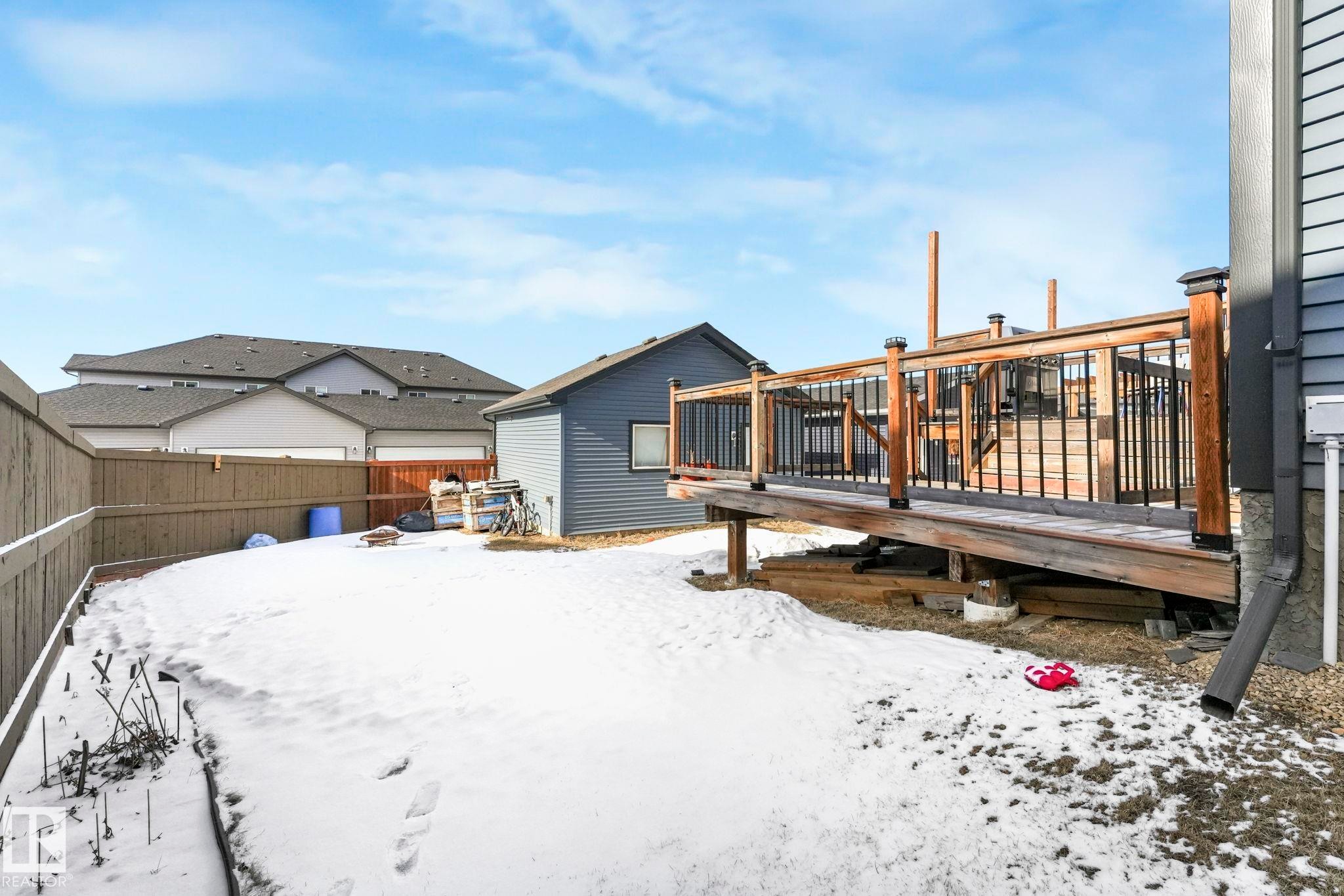 Snow covered back of property featuring a deck and a fenced backyard - 2428 Wonnacott Crest, Edmonton, AB - Outdoor With Deck Patio Veranda