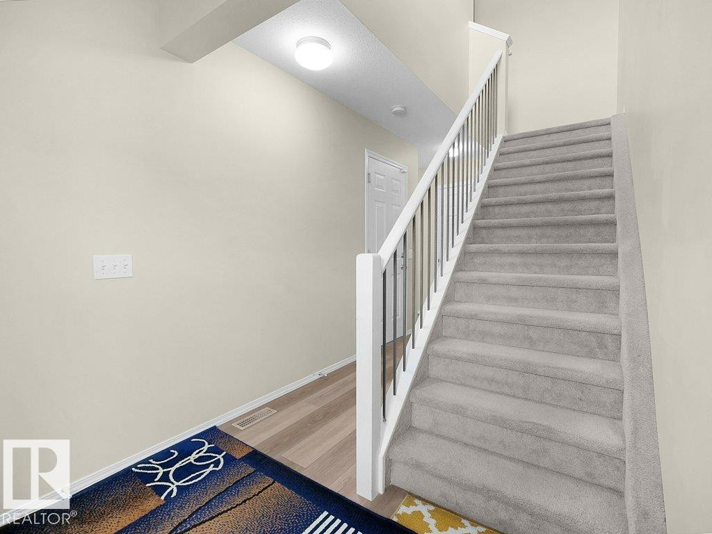 Stairway featuring baseboards and wood finished floors - 196 230 Edwards Drive, Edmonton, AB - Indoor Photo Showing Other Room