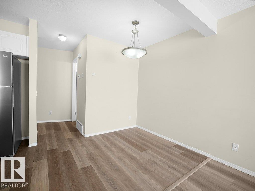 Unfurnished dining area featuring dark wood finished floors and beamed ceiling - 196 230 Edwards Drive, Edmonton, AB - Indoor Photo Showing Other Room