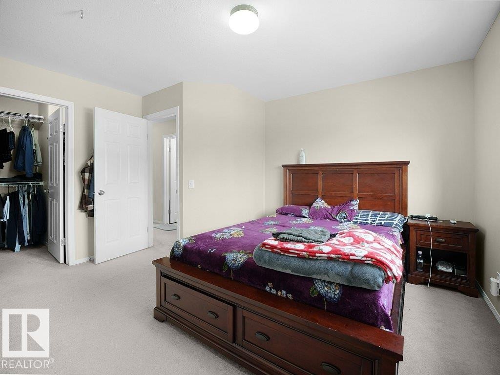 Bedroom featuring light carpet and a walk in closet - 196 230 Edwards Drive, Edmonton, AB - Indoor Photo Showing Bedroom