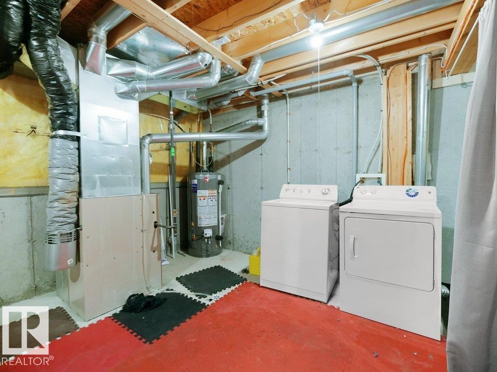 Laundry area featuring heating unit, water heater, unfinished concrete flooring, and washing machine and clothes dryer - 196 230 Edwards Drive, Edmonton, AB - Indoor Photo Showing Laundry Room