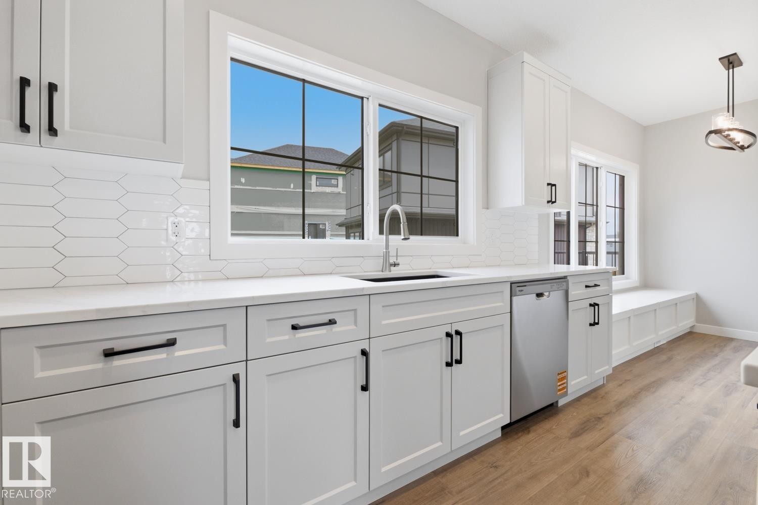 Kitchen features white shaker cabinetry, white countertops, a mosaic tile backsplash, stainless steel appliances, and wood-finish flooring - 30 Chartres Close Nw, St. Albert, AB