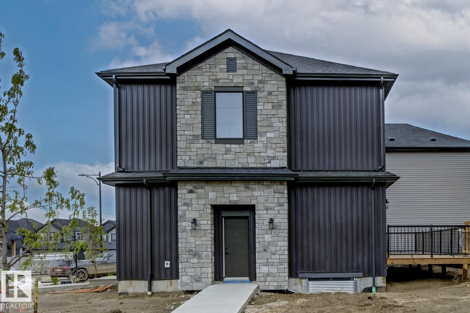 Contemporary two-story residence featuring a gray stone facade and dark vertical siding - 30 Chartres Close Nw, St. Albert, AB