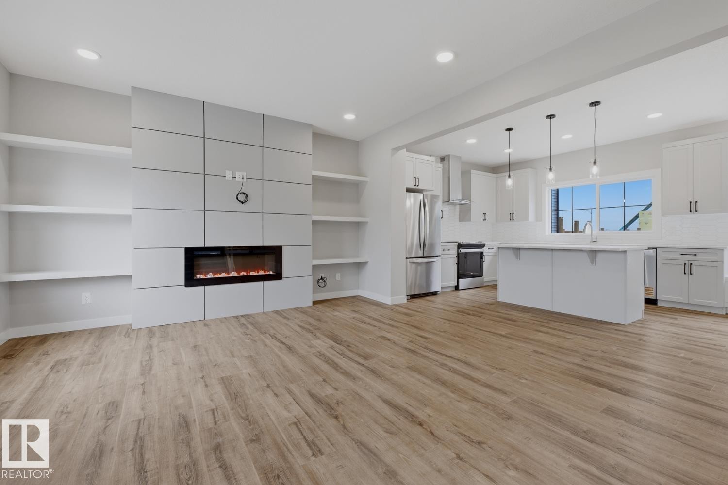 Open-concept living space featuring wood-finish flooring, a modern electric fireplace, built-in shelving, and recessed lighting - 30 Chartres Close Nw, St. Albert, AB