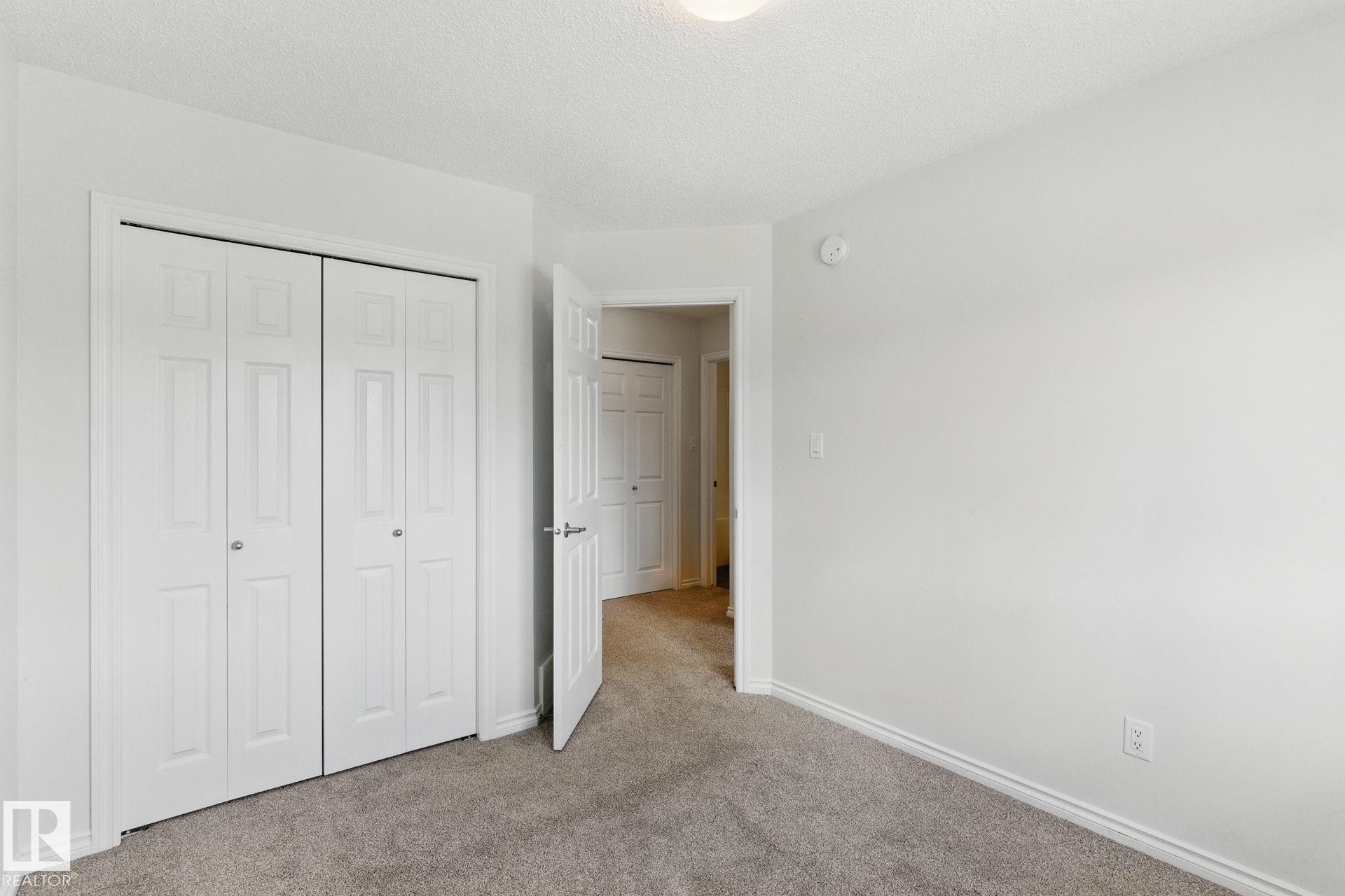 This room features light gray carpeting, white walls, and a ceiling light fixture - 2416 Wonnacott Crest Sw, Edmonton, AB - Indoor