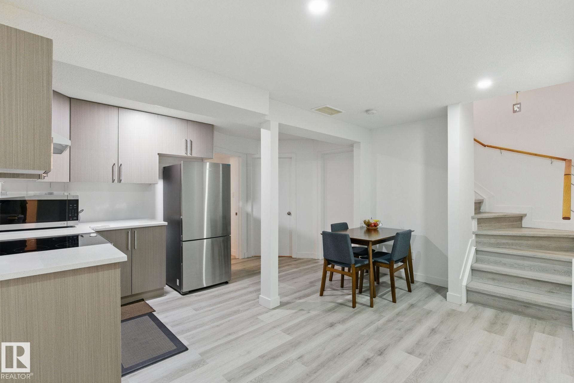 The property features a kitchen area with light wood cabinetry, stainless steel appliances, and light-colored countertops - 2416 Wonnacott Crest Sw, Edmonton, AB - Indoor Photo Showing Kitchen