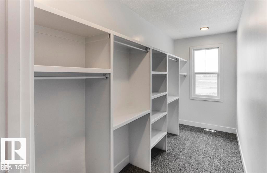 This room features extensive built-in shelving, hanging rods, and a window providing natural light - 63 Jubilation Drive, St. Albert, AB - Indoor With Storage