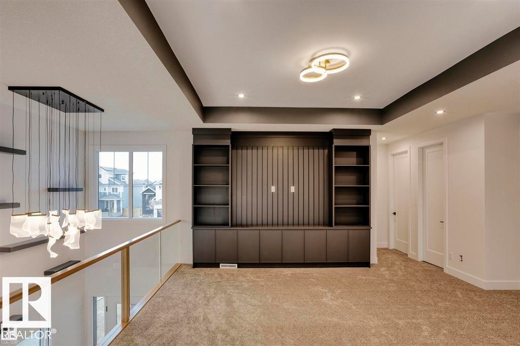 Spacious area featuring built-in shelving, recessed lighting, and a modern chandelier - 63 Jubilation Drive, St. Albert, AB - Indoor Photo Showing Other Room