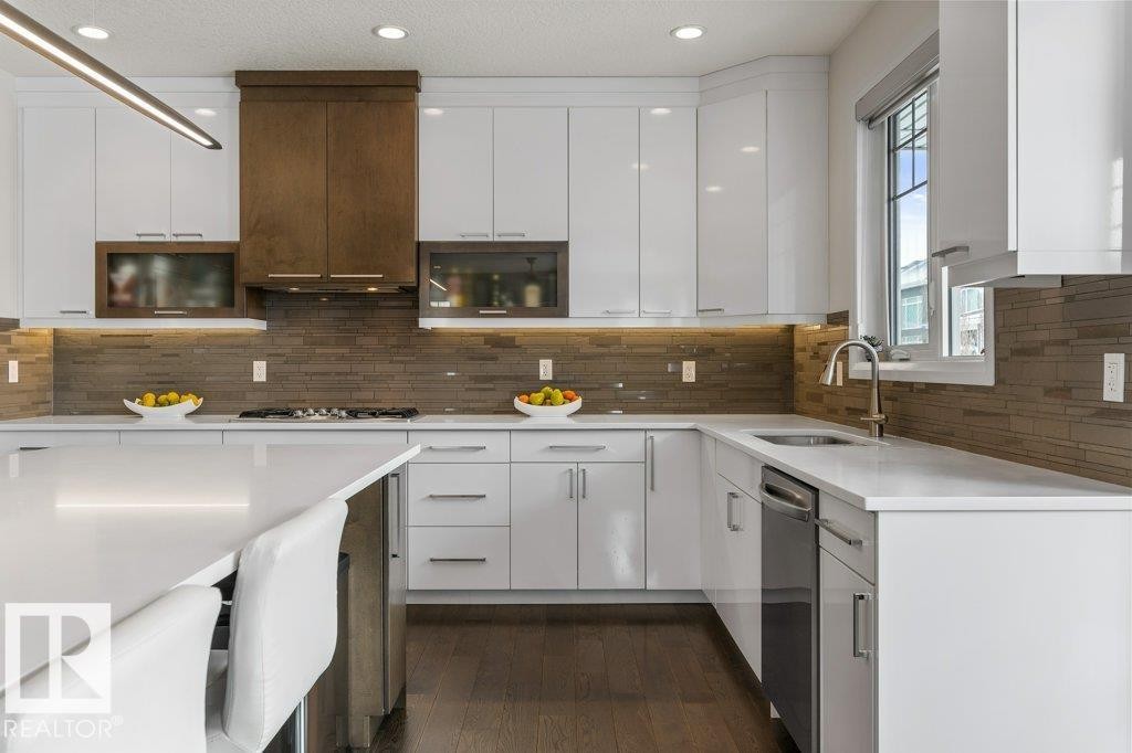 Kitchen Features Dark Hardwood Flooring, Two Tone Kitchen Cabinets, Gas Stove, Wall Oven, and White Quartz Counters - 4476 Suzanna Crescent, Edmonton, AB - Indoor Photo Showing Kitchen With Upgraded Kitchen
