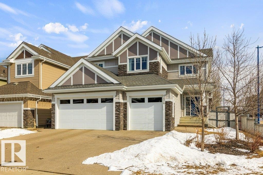 Front Exterior of Home featuring Triple Car Garage, Vinyl and Stone Exterior, and Corner Lot - 4476 Suzanna Crescent, Edmonton, AB - Outdoor With Facade