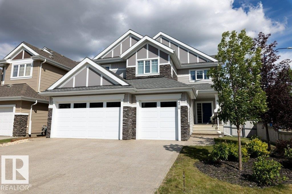 Summer View of Front Exterior of Home featuring Triple Car Garage, Vinyl and Stone Exterior, and Corner Lot - 4476 Suzanna Crescent, Edmonton, AB - Outdoor With Facade