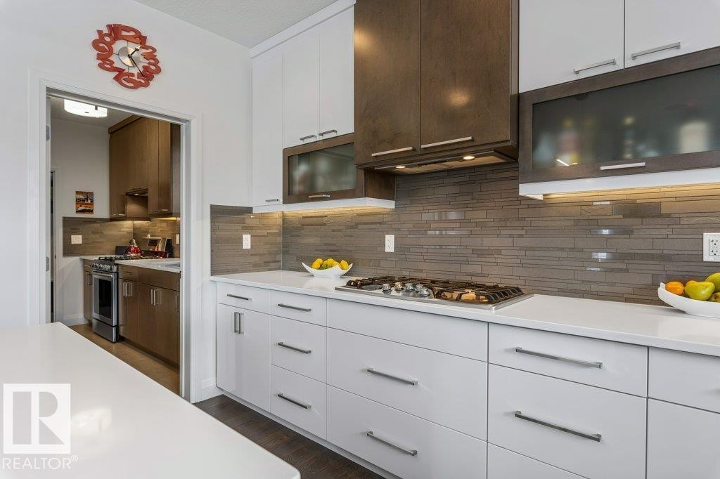 Kitchen Features Dark Hardwood Flooring, Two Tone Kitchen Cabinets, Gas Stove, Wall Oven, and White Quartz Counters - 4476 Suzanna Crescent, Edmonton, AB - Indoor Photo Showing Kitchen With Upgraded Kitchen